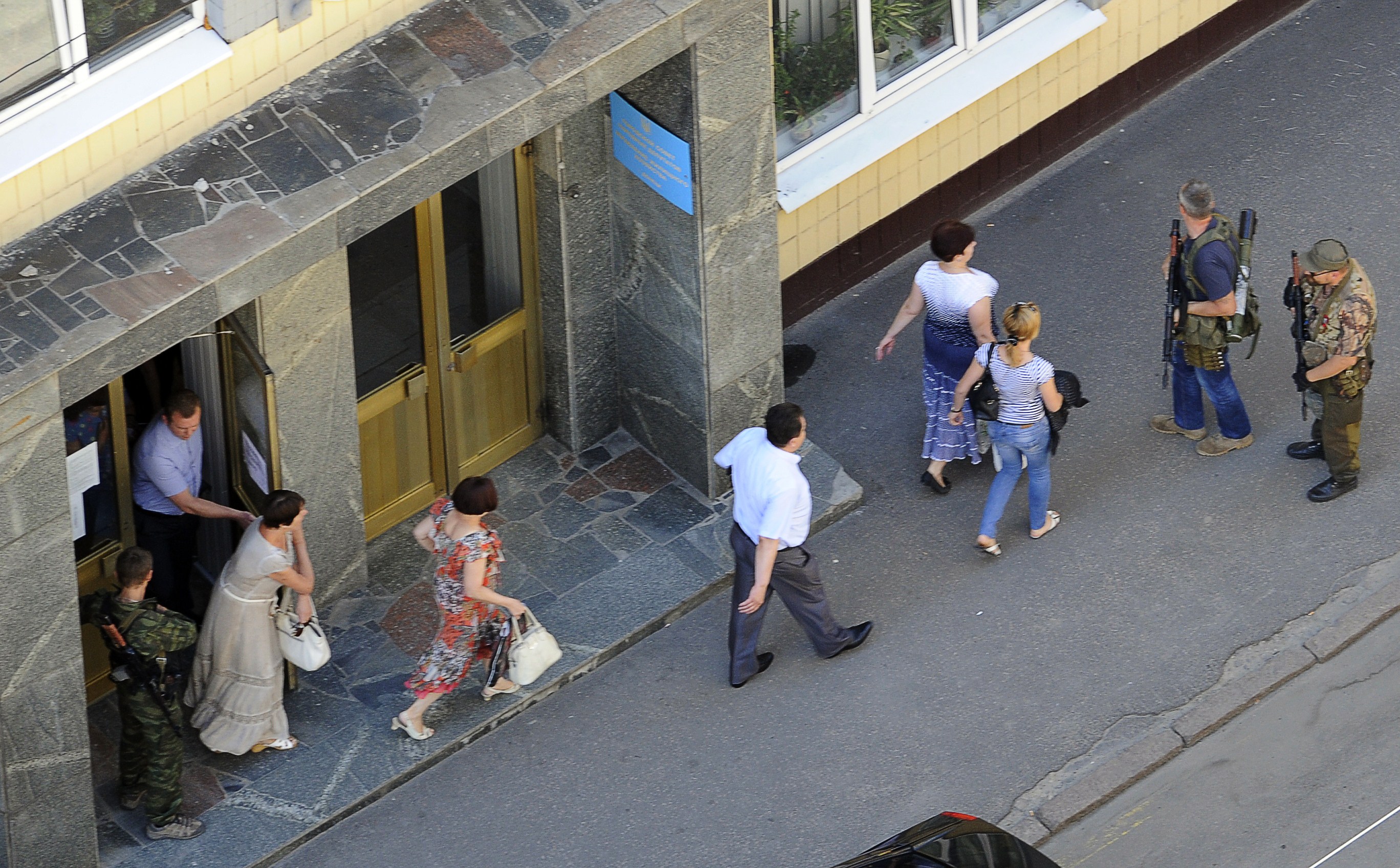 Employees leave their offices escorted by pro-Russian militants occupying the building for sniper positions in the centre of the eastern Ukrainian city of Donetsk on July 1, 2014. Ukrainian tanks and fighter bombers on July 1 launched a ferocious assault against pro-Russian separatist insurgents after rejecting European attempts to save a tenuous 10-day truce. AFP PHOTO/ ALEXANDER KHUDOTEPLY (Photo credit should read Alexander KHUDOTEPLY/AFP/Getty Images)