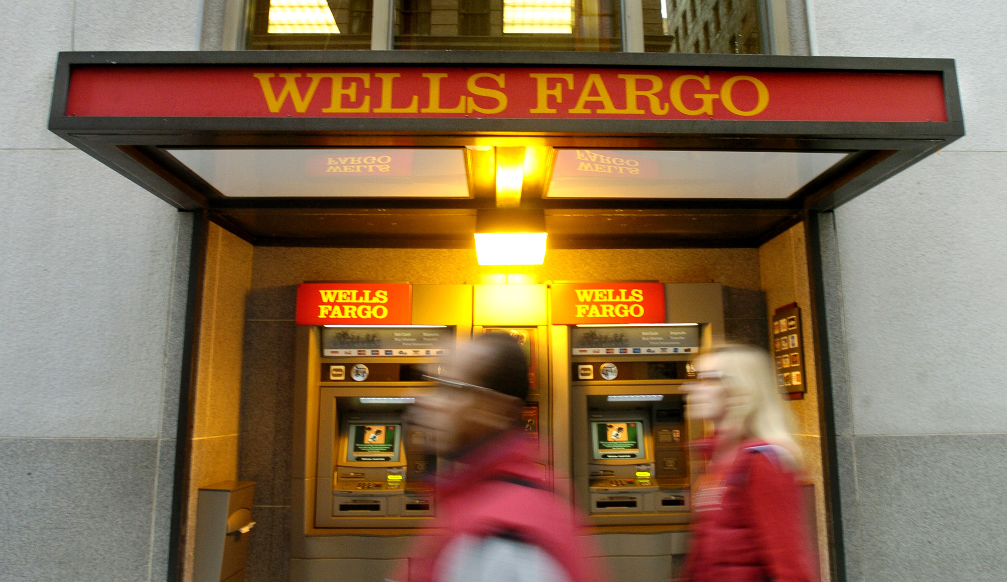 Pedestrians pass an ATM outside Wells Fargo & Co.'s San Fran