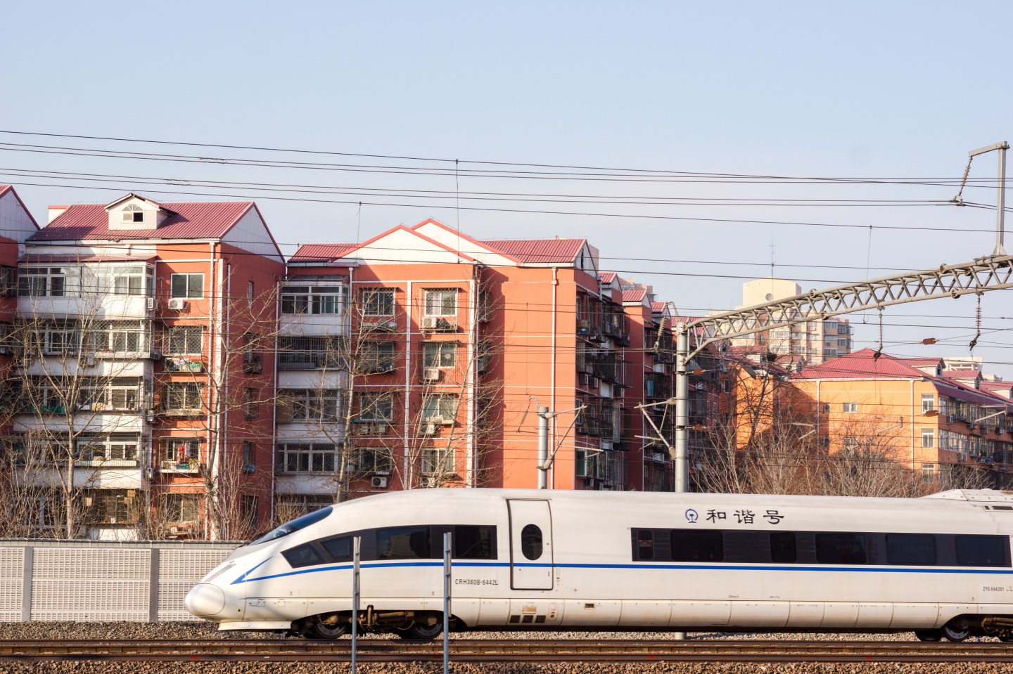 A high speed train is driving past a residential district.