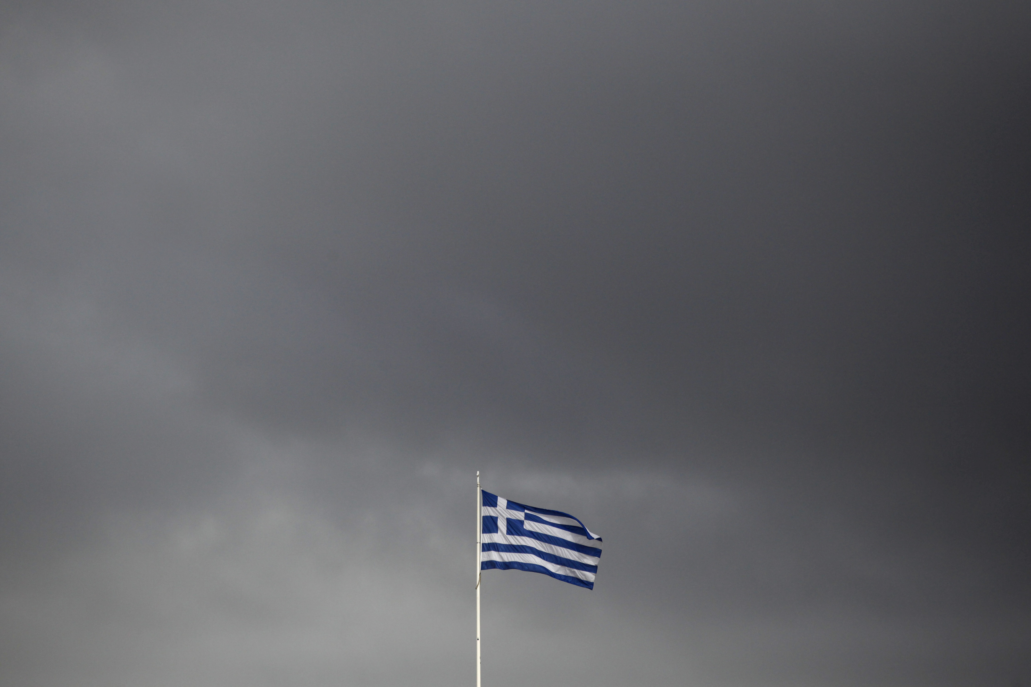 A European Union (EU) flag flies above the Greek parliament in Athens, Greece, on Tuesday, Feb. 24, 2015. Greece moved closer to winning an extension of financial aid after the head of the group of euro-region finance ministers said creditors were favorable toward the government’s package of new economic measures. Photographer: Kostas Tsironis/Bloomberg