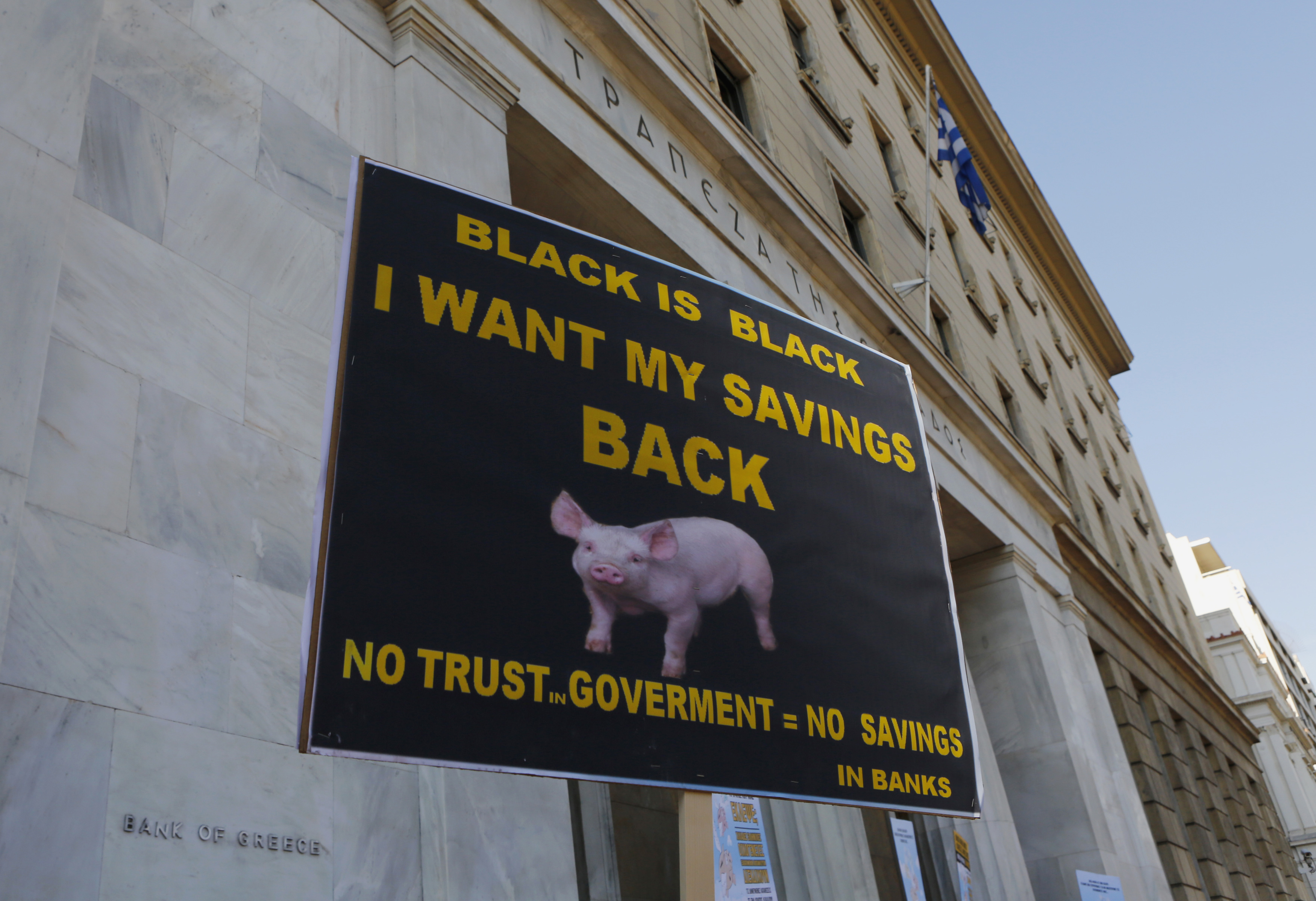 A Greek bondholder holds a sign as he takes part in a protest outside the Central Bank of Greece in Athens