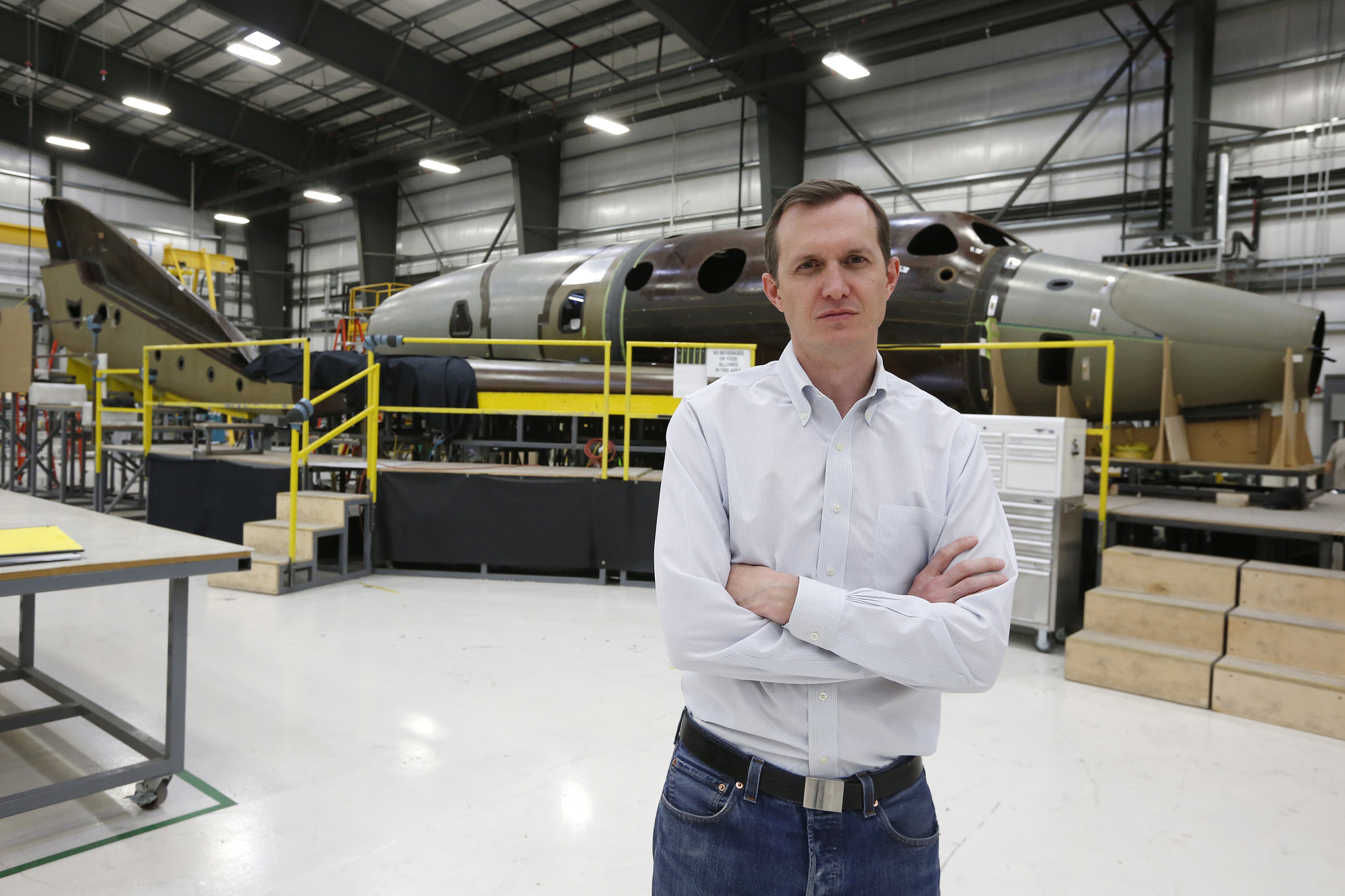 Virgin Galactic's CEO George T. Whitesides stands in front of their new spaceship N202VG, which the company began building 2 and a half years ago, in a hangar at Mojave Air and Space Port in Mojave, California