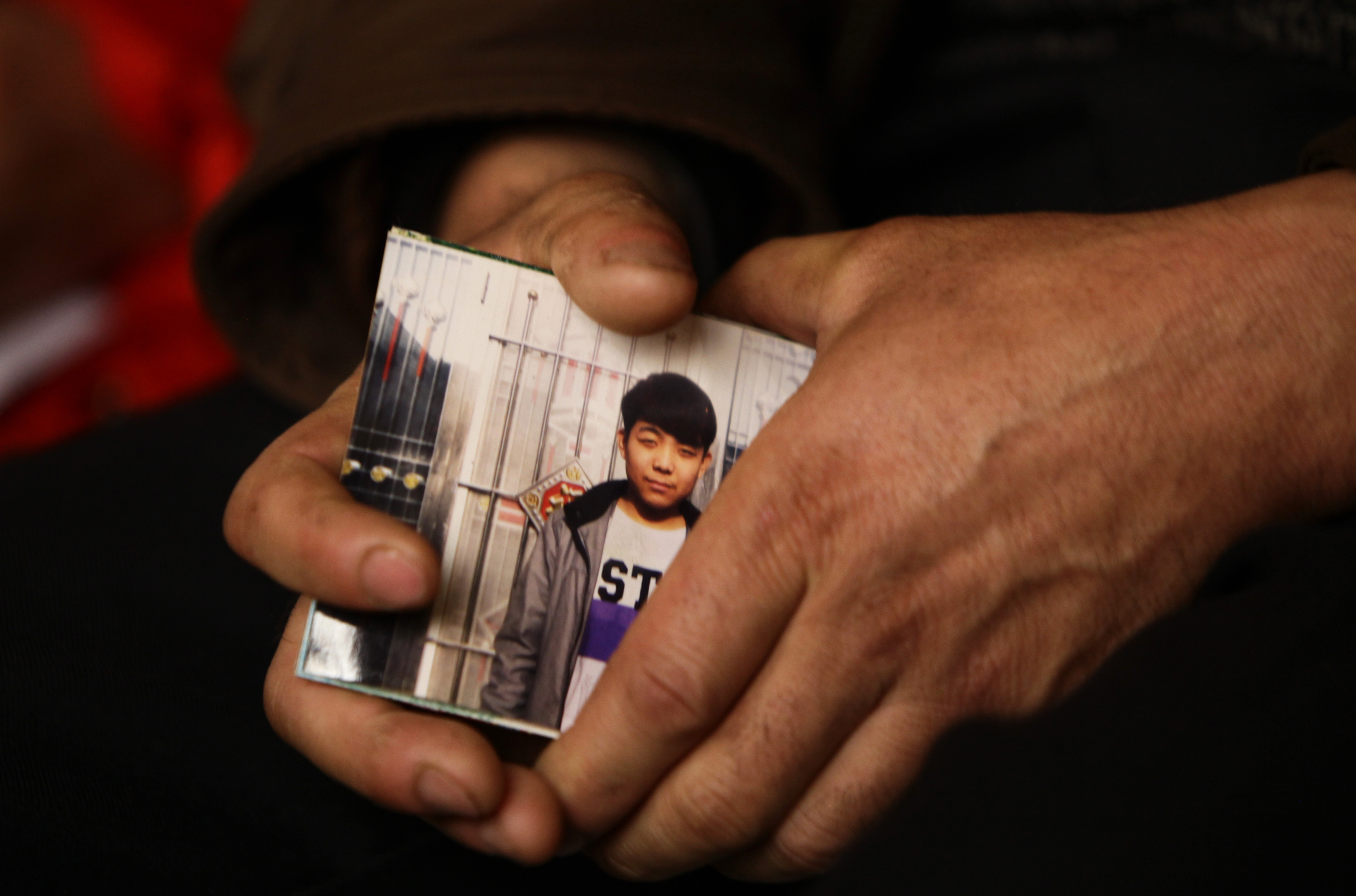 The father of the 15-year-old Pegatron worker who died of pneumonia, holds his son's picture at a news conference in Beijing