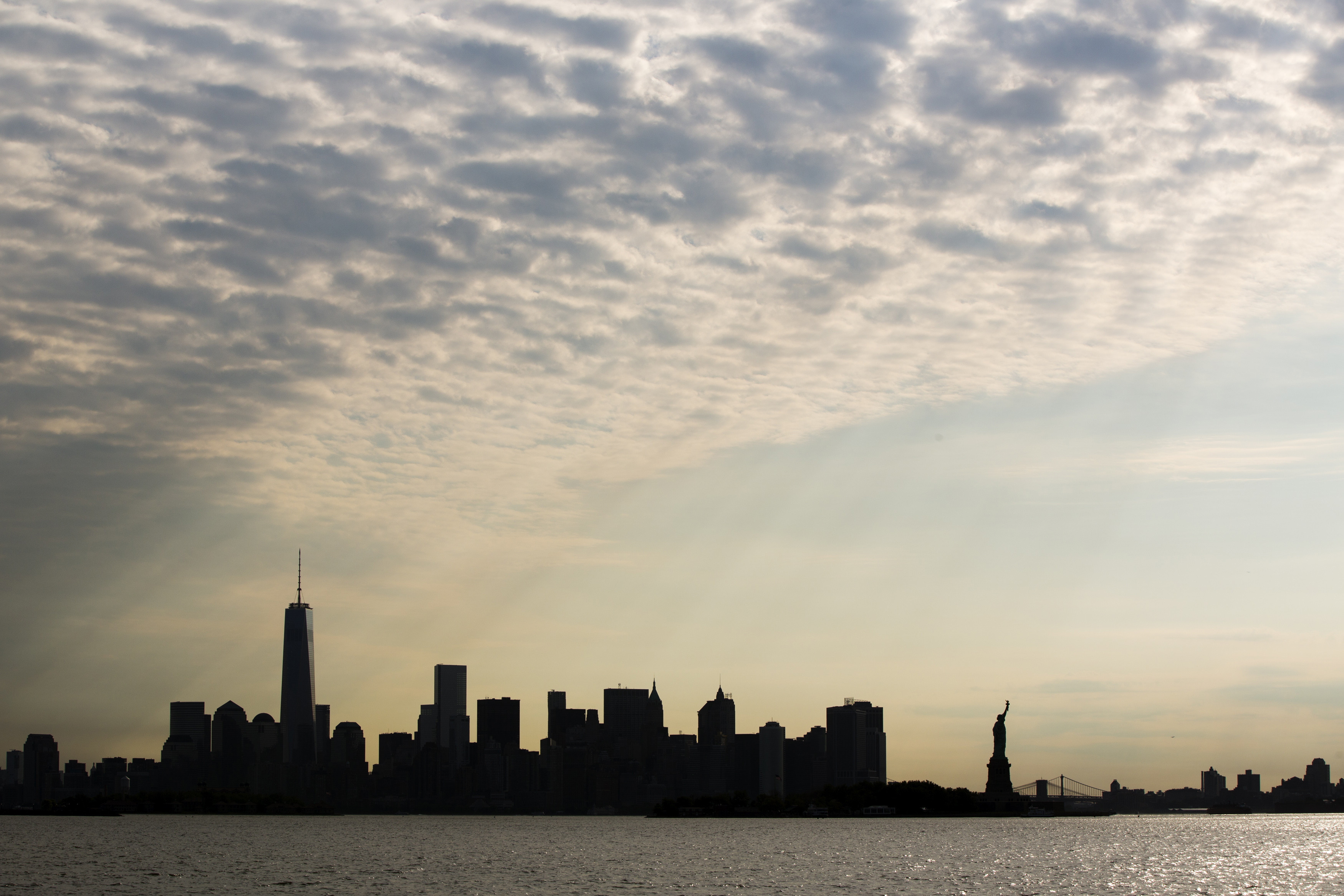 The sun rises behind the Statue of Liberty and the skyline of lower Manhattan in New York