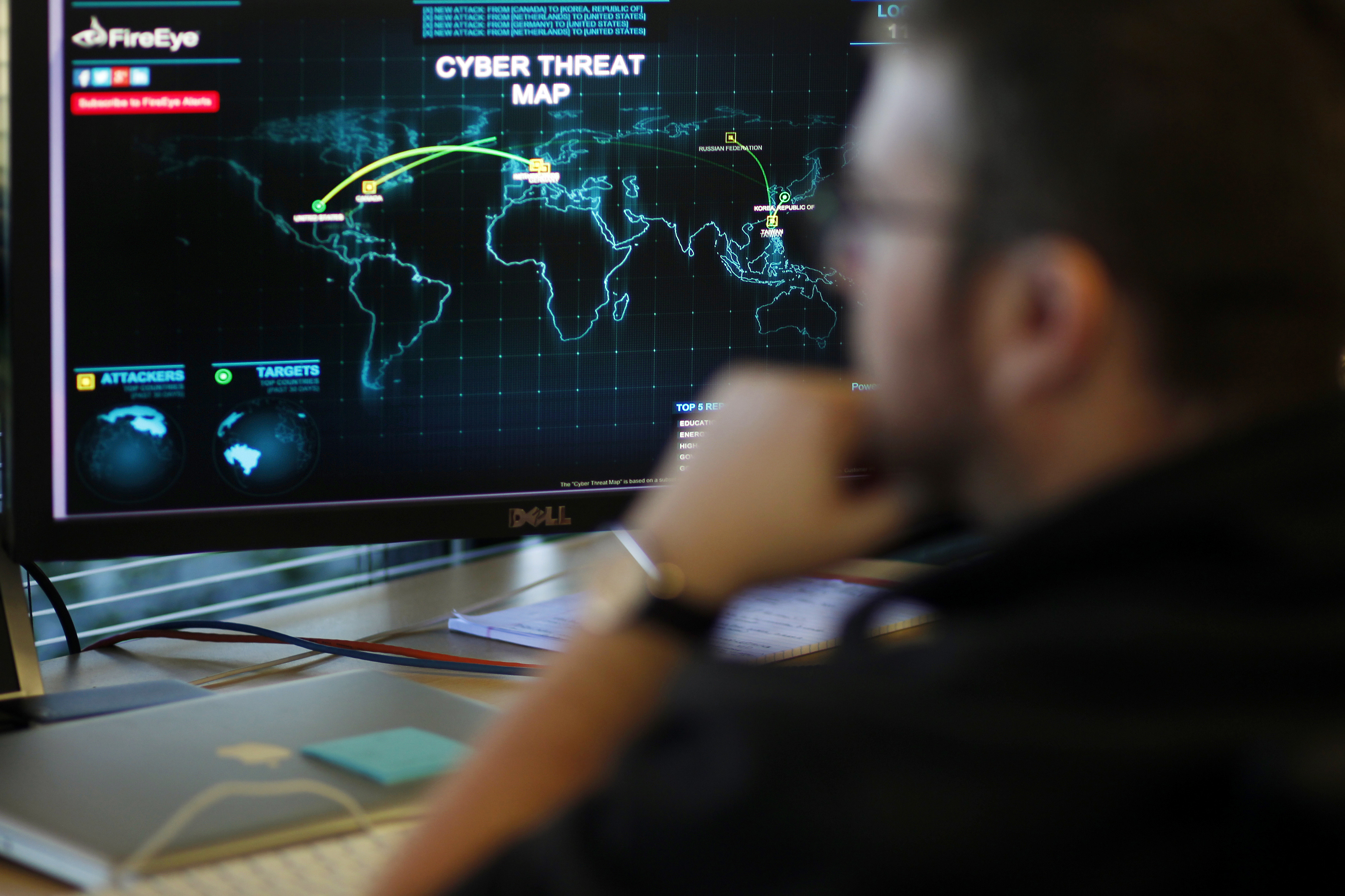 FireEye information analyst works in front of a screen showing a near real-time map tracking cyber threats at the FireEye office in Milpitas, California