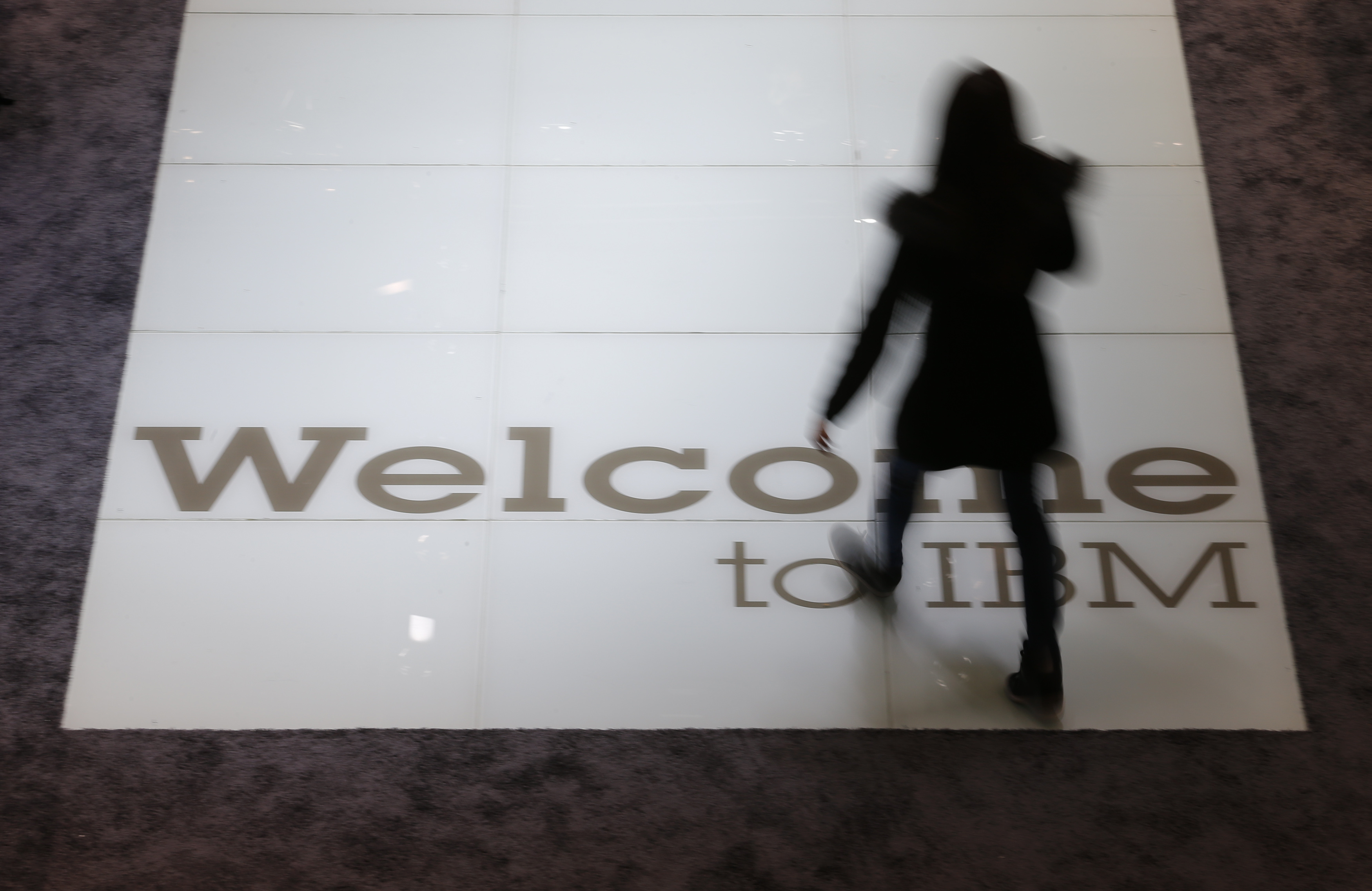 A woman walks over a welcoming sign at the booth of IBM at the CeBIT trade fair in Hanover