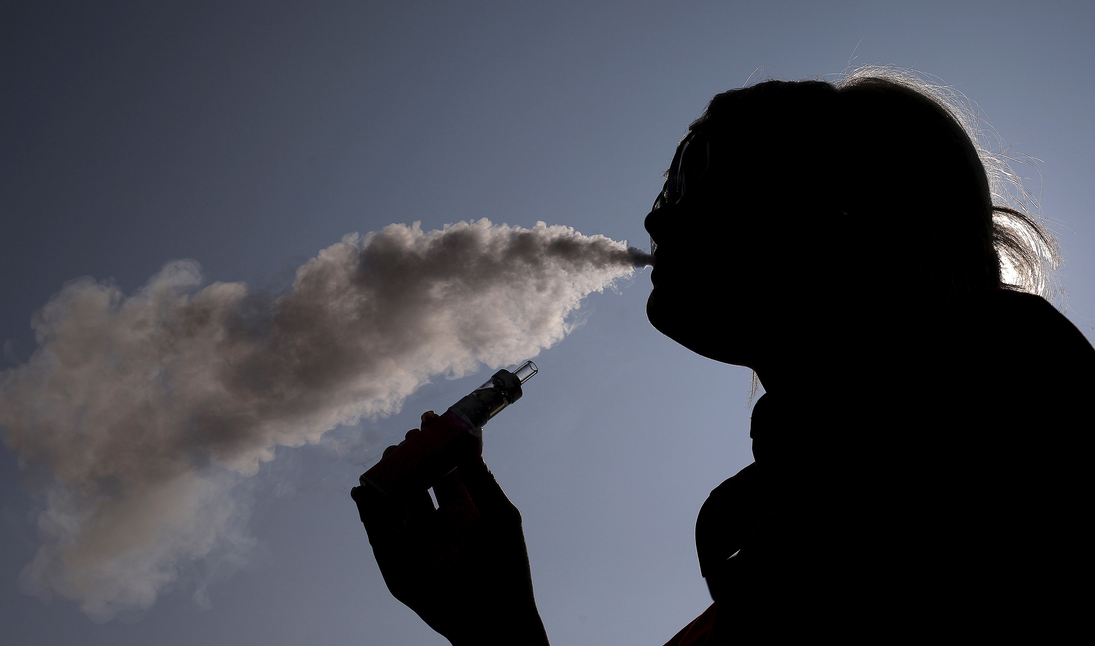 A woman exhales vapour from an e-cigarette outside the offices of British e-cigarette manufacturer Totally Wicked in Blackburn
