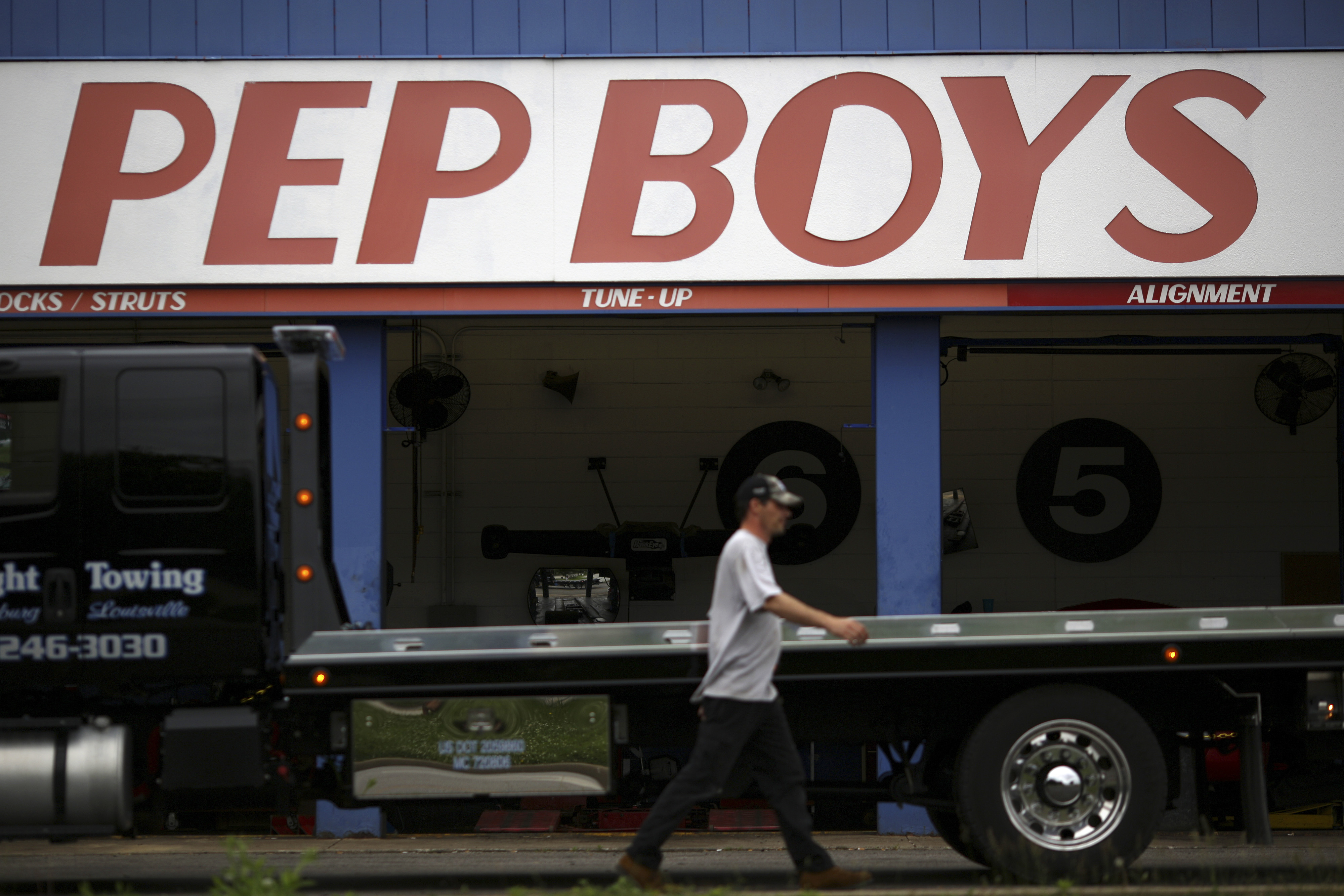 A tow truck driver walks past a Pep Boys Company auto repair and service center in Clarksville, Indiana, U.S. on Wednesday, June 3, 2015. Pep Boys earnings are scheduled to be released on June 8. Photographer : Luke Sharrett / Bloomberg