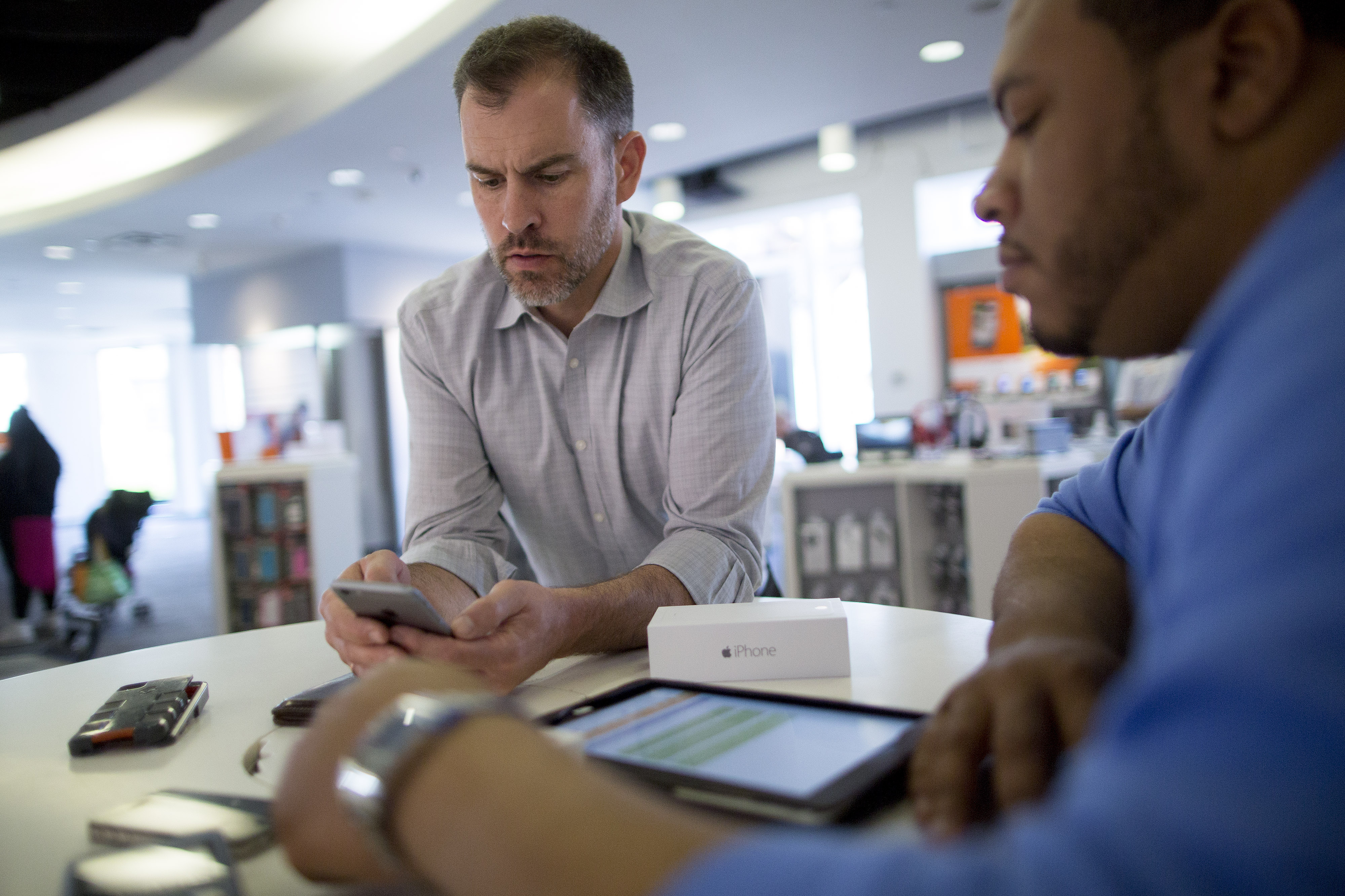 Retail sales consultant Ahmal Warner, right, helps customer Joel Nelson set up his new iPhone 6 at an AT&T store in Washington, D.C., U.S., on Tuesday, April 21, 2015.
