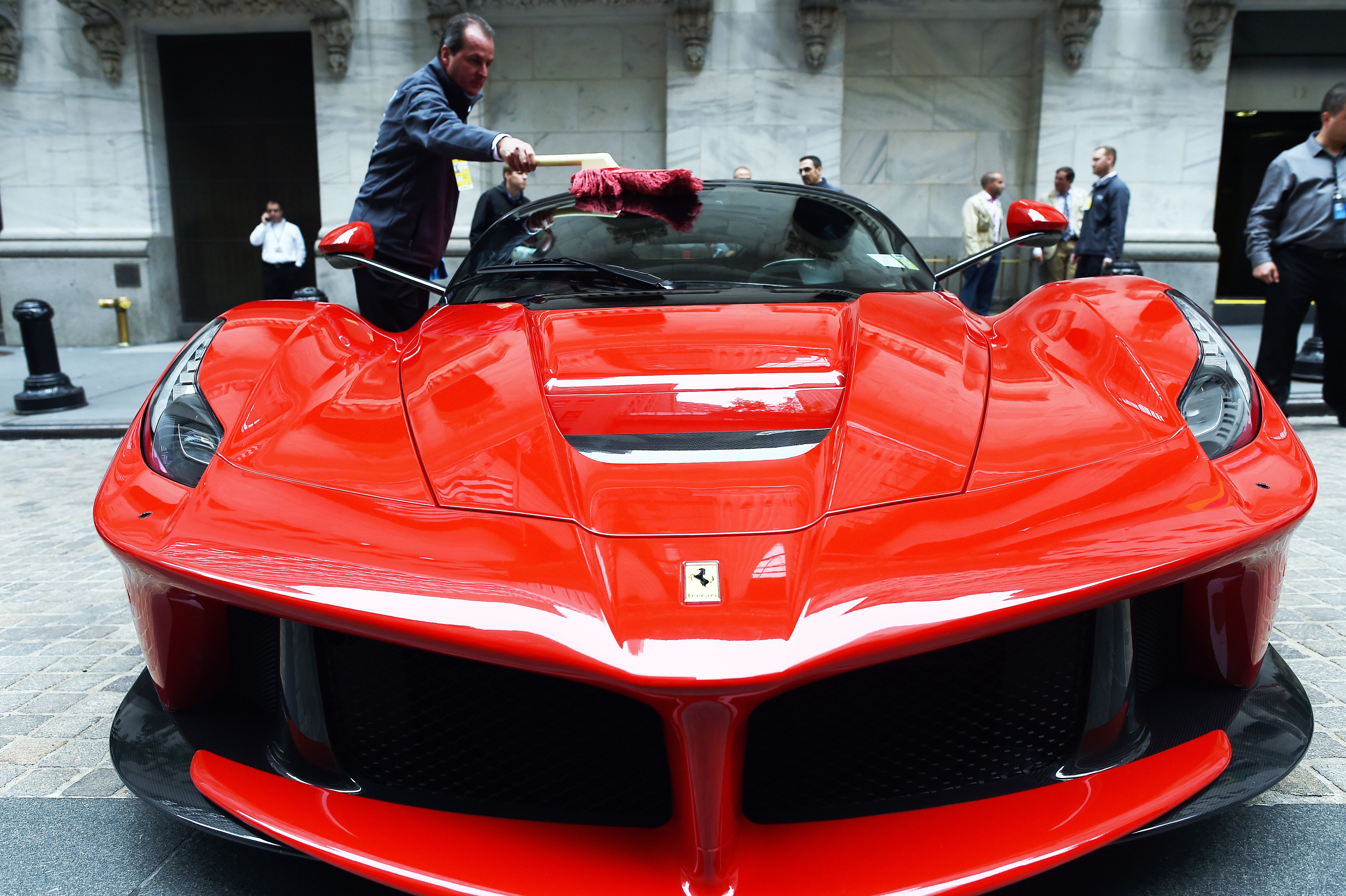 An employee shines a Ferrari LaFerrari displayed in front of the New York Stock Exchange (NYSE) on October, 13, 2014 in New York.