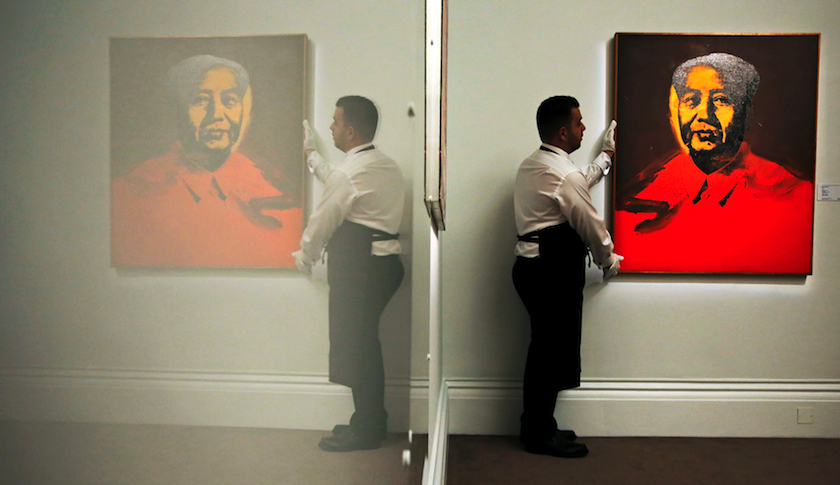 An employee with Andy Warhol's "Mao" at Sotheby's auction house in London
