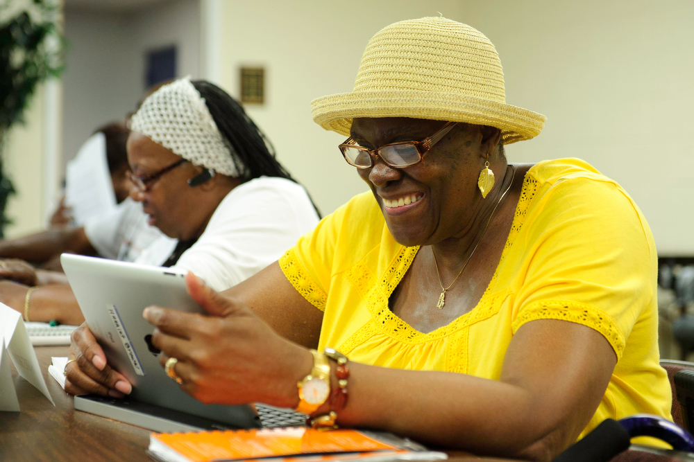 Harriet Carter-Brown, 63, of Washington, DC, smiles as she looks at photos of lighthouses on her iPad during the twice weekly Connect to Community class in the basement of Shiloh Baptist Church in Washington, DC, on July 9, 2013. The program is sponsored by the AARP Foundation.