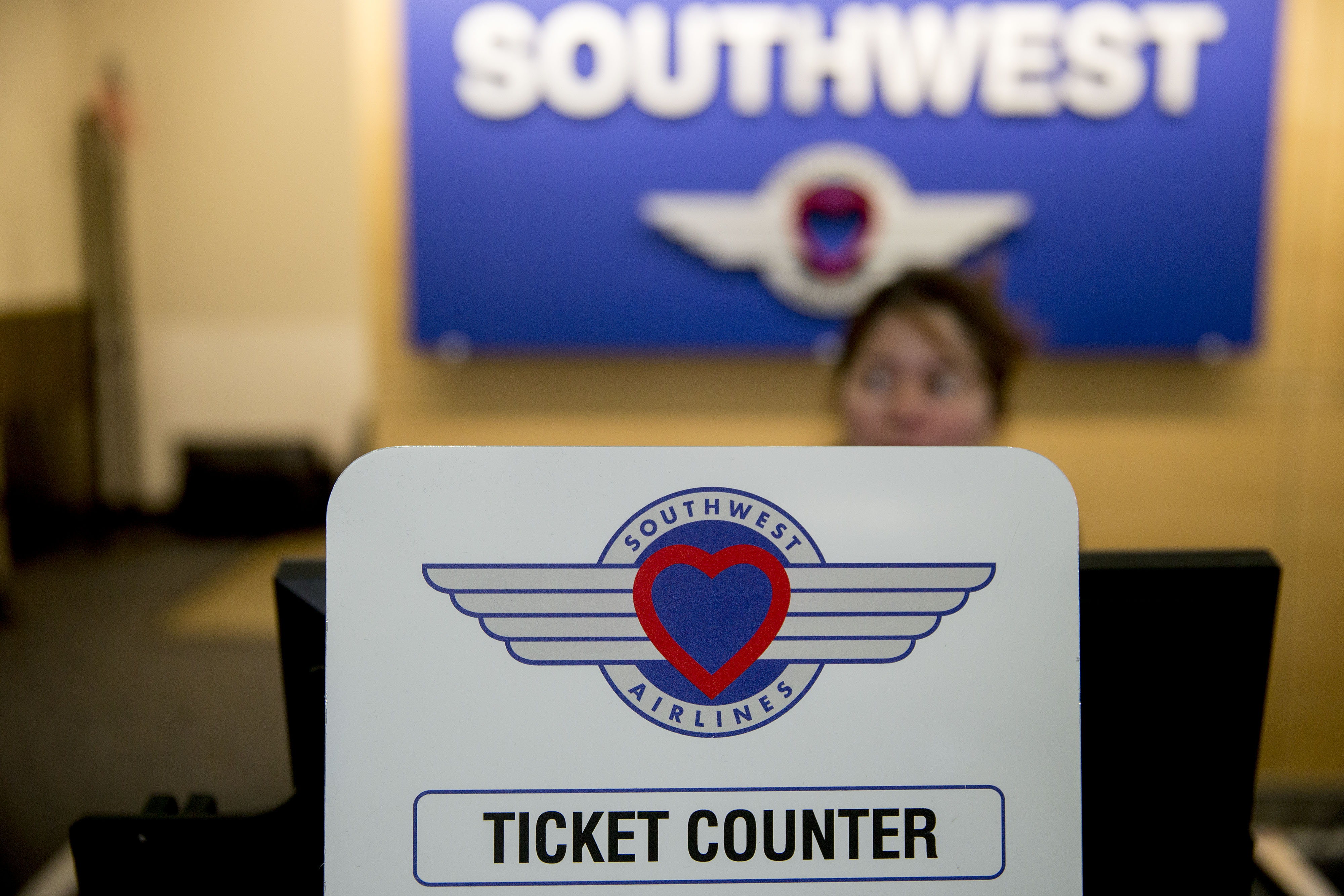 An attendant stands behind a ticket counter sign at the Southwest Airlines check-in counter at Ronald Reagan National Airport in Washington, D.C.