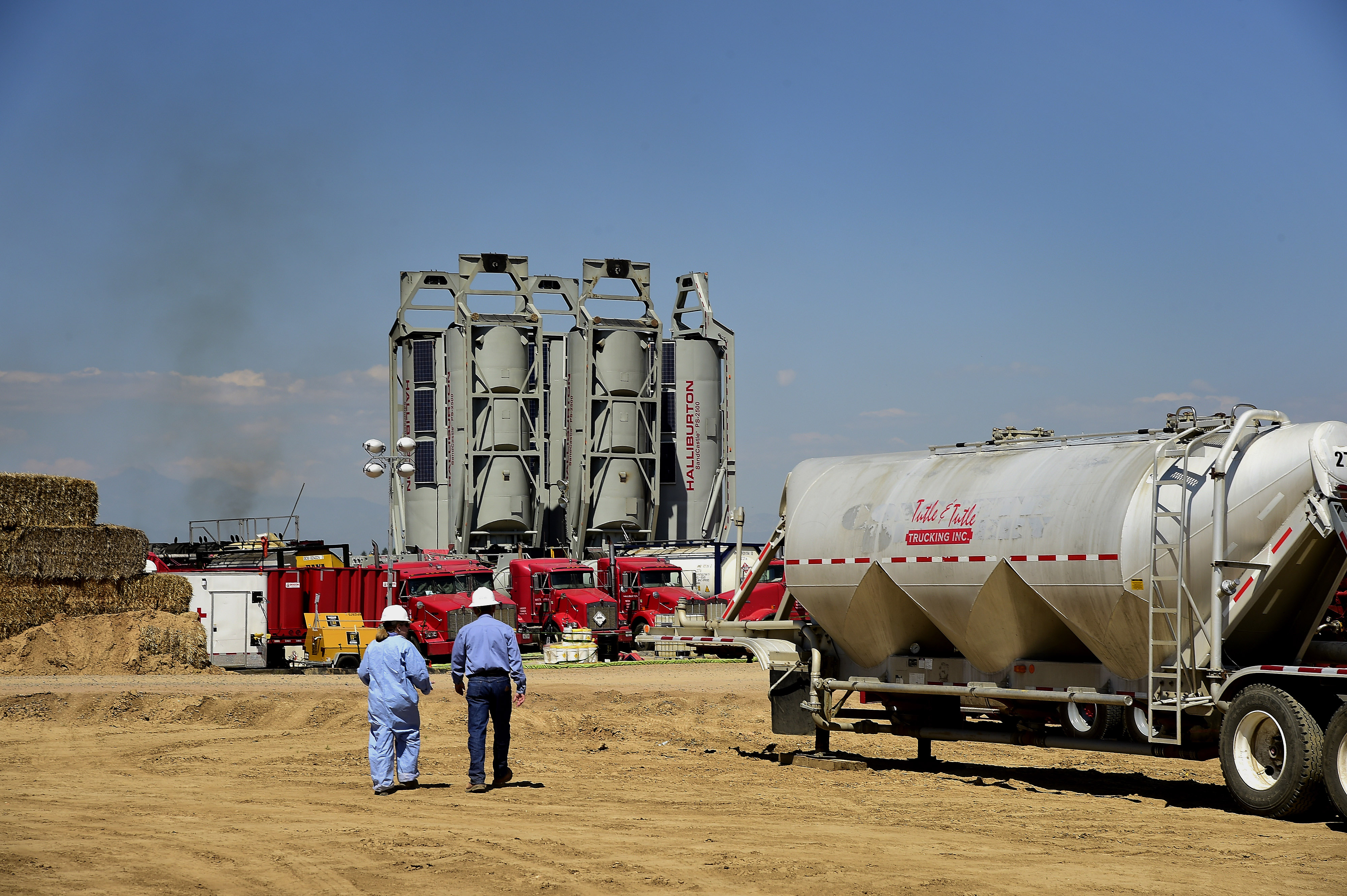 Workers walk towards Halliburton's "sand castles" at an Anadarko Petroleum Corp. hydraulic fracturing site north of Dacono, Colorado, U.S.