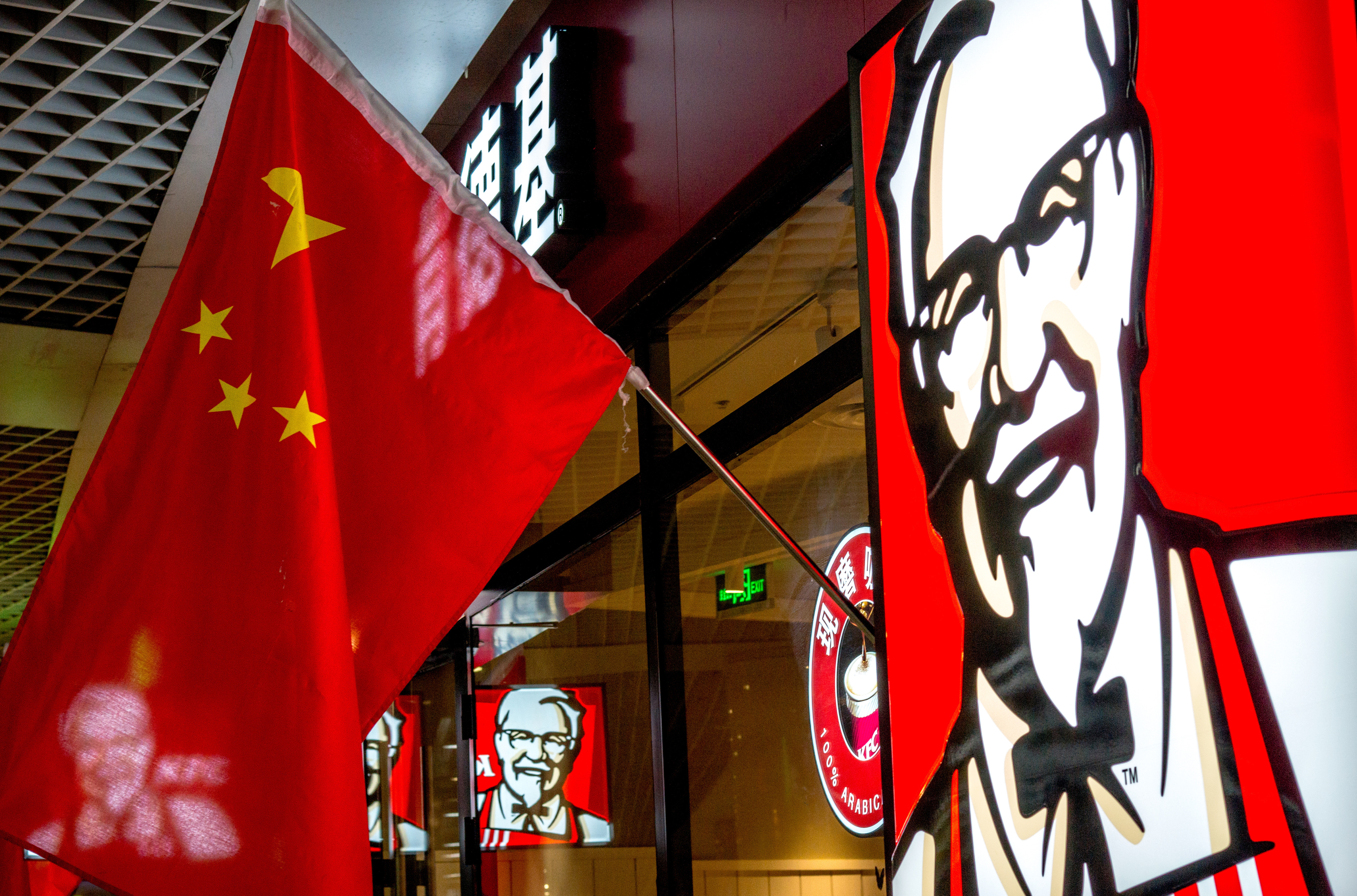 TIANJIN, CHINA - 2015/02/21: A KFC restaurant hangs up China's national flags in lunar new year.  KFC restaurants in China will start selling freshly ground coffee in 2015 to become a lower-cost “premium” alternative to Starbucks. The initiative began earlier this year and is expected to perform in 2,500 KFCs in China by the end of this year. (Photo by Zhang Peng/LightRocket via Getty Images)