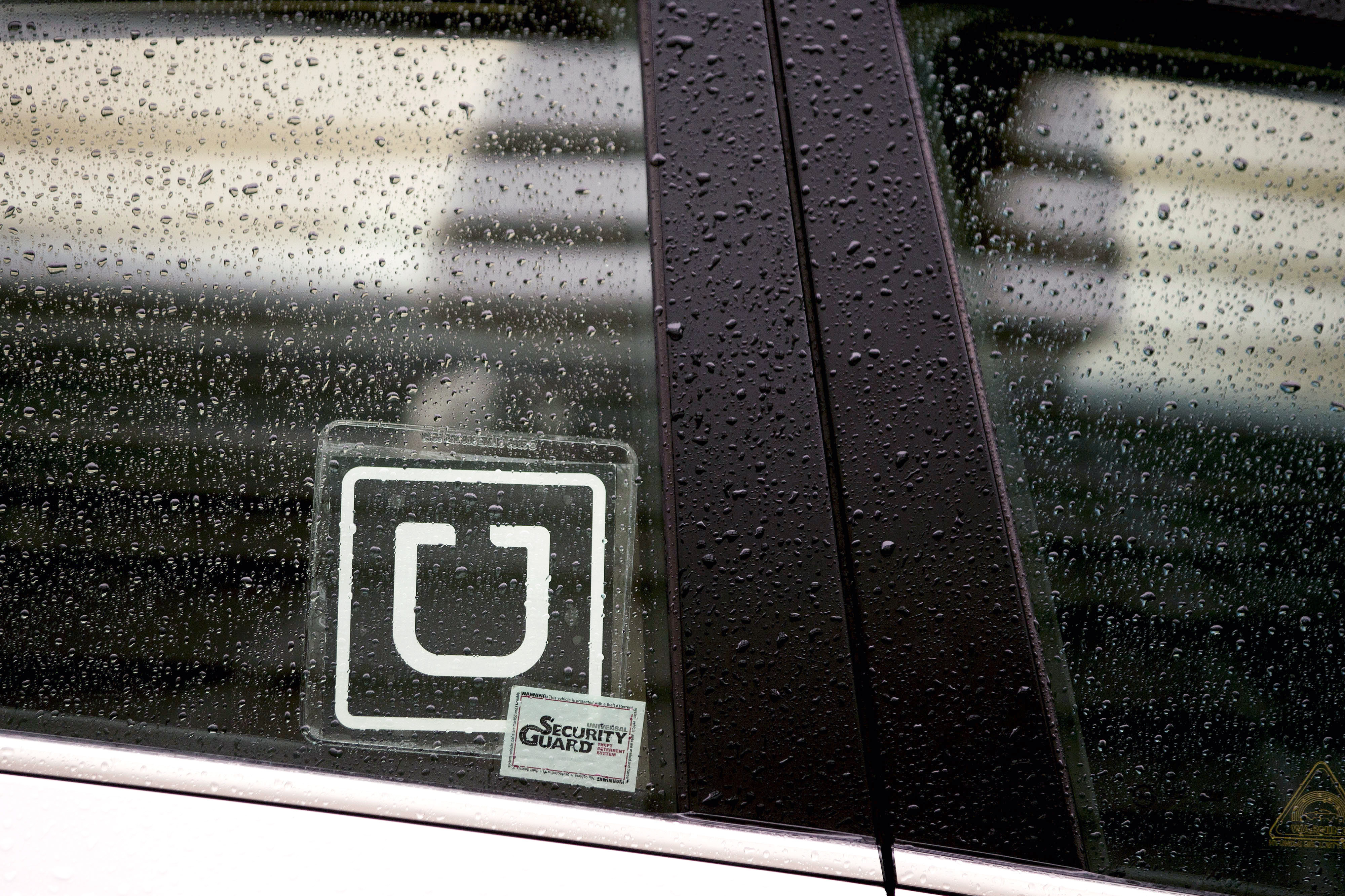 The Uber logo is displayed on the window of a vehicle