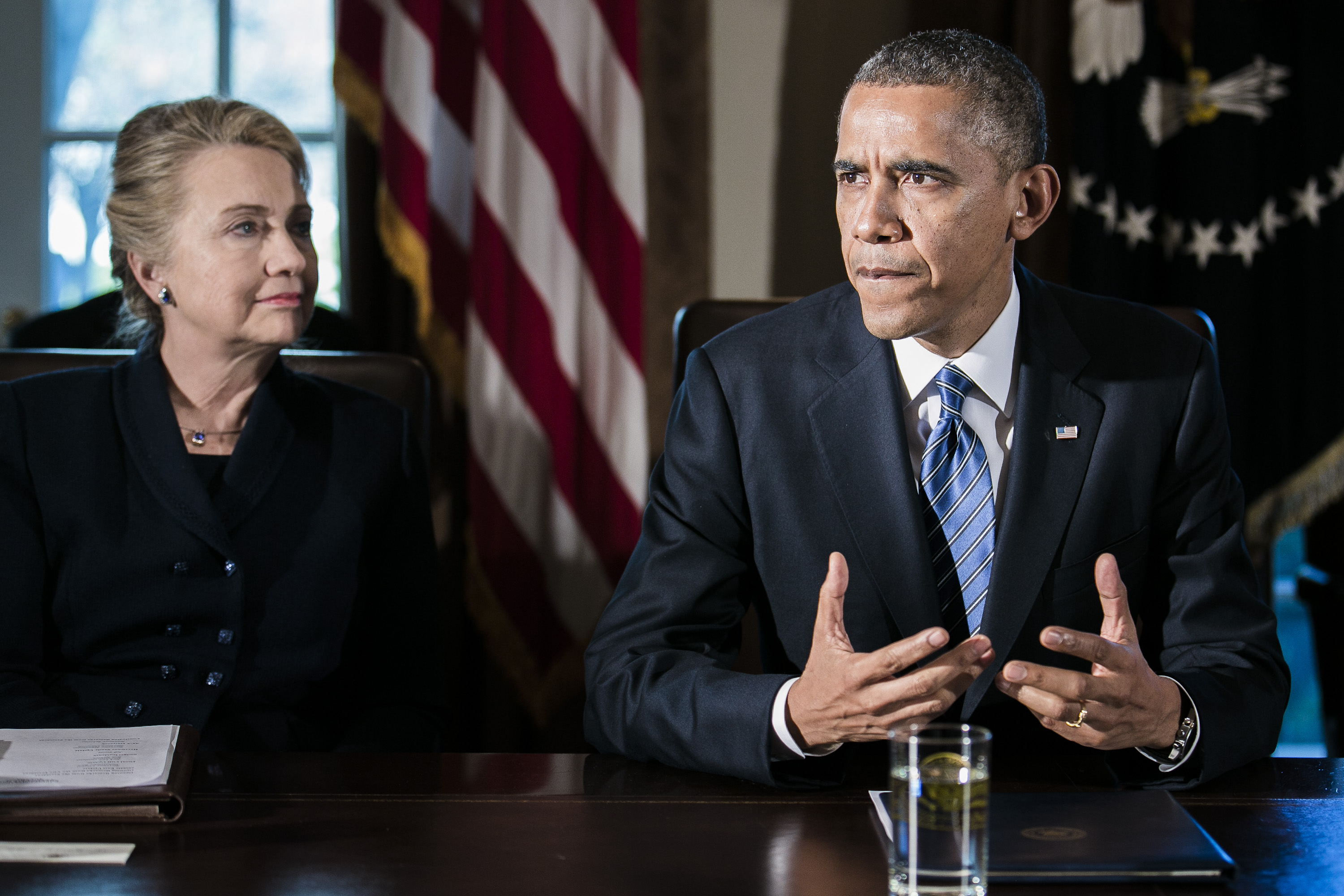 U.S. President Barack Obama, right, speaks as Department of State Secretary Hillary Clinton listens at a cabinet meeting at the White House on Nov. 28, 2012 in Washington, D.C. The president met yesterday with small business owners and today with the chief executives of major corporations in ongoing talks about the looming fiscal cliff.Photographer: T.J. Kirkpatrick/Bloomberg
