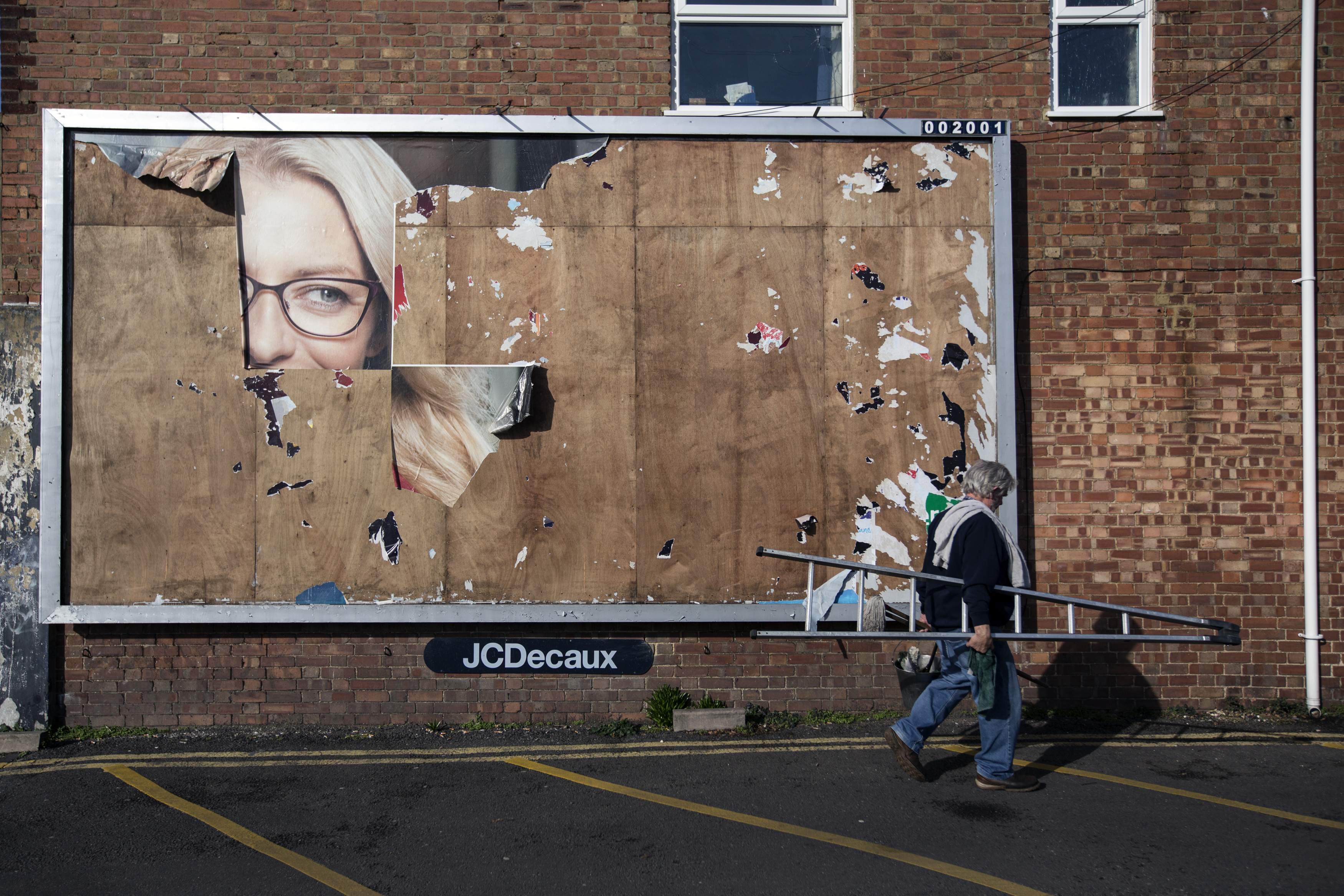 A Man Walks Past the Remains of an Old Billboard Advert