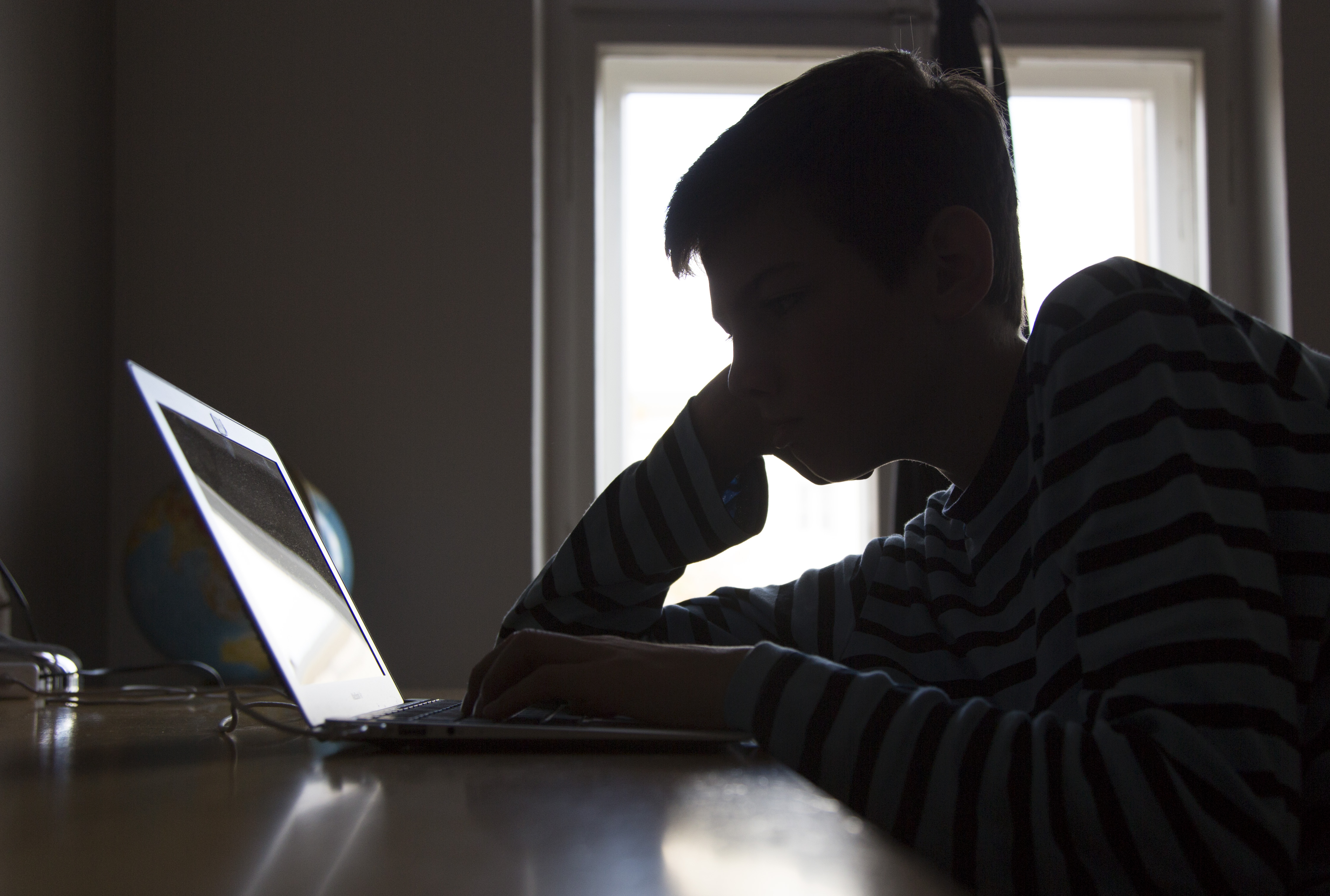 A Boy Sitting At A Laptop