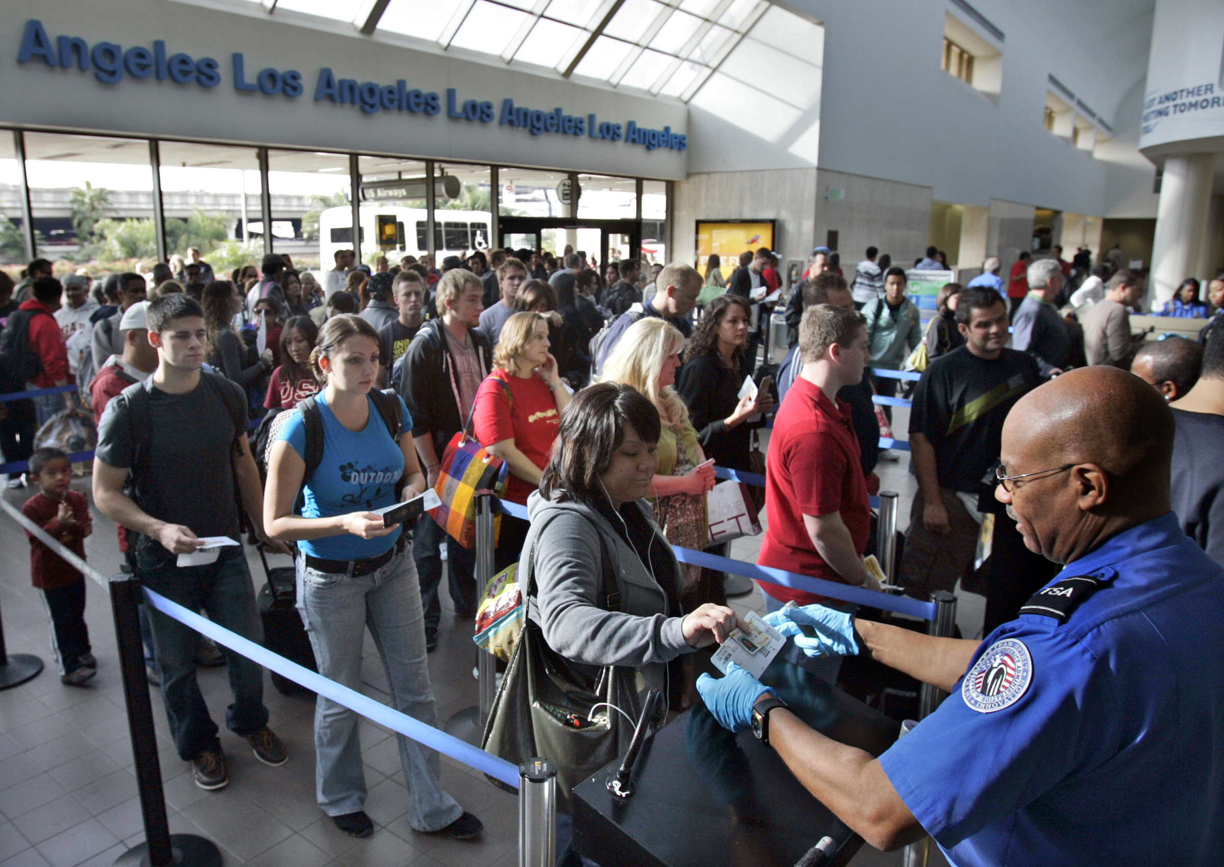 Travelers form a long security check line that is extended out of departure lounge at Los Angeles a