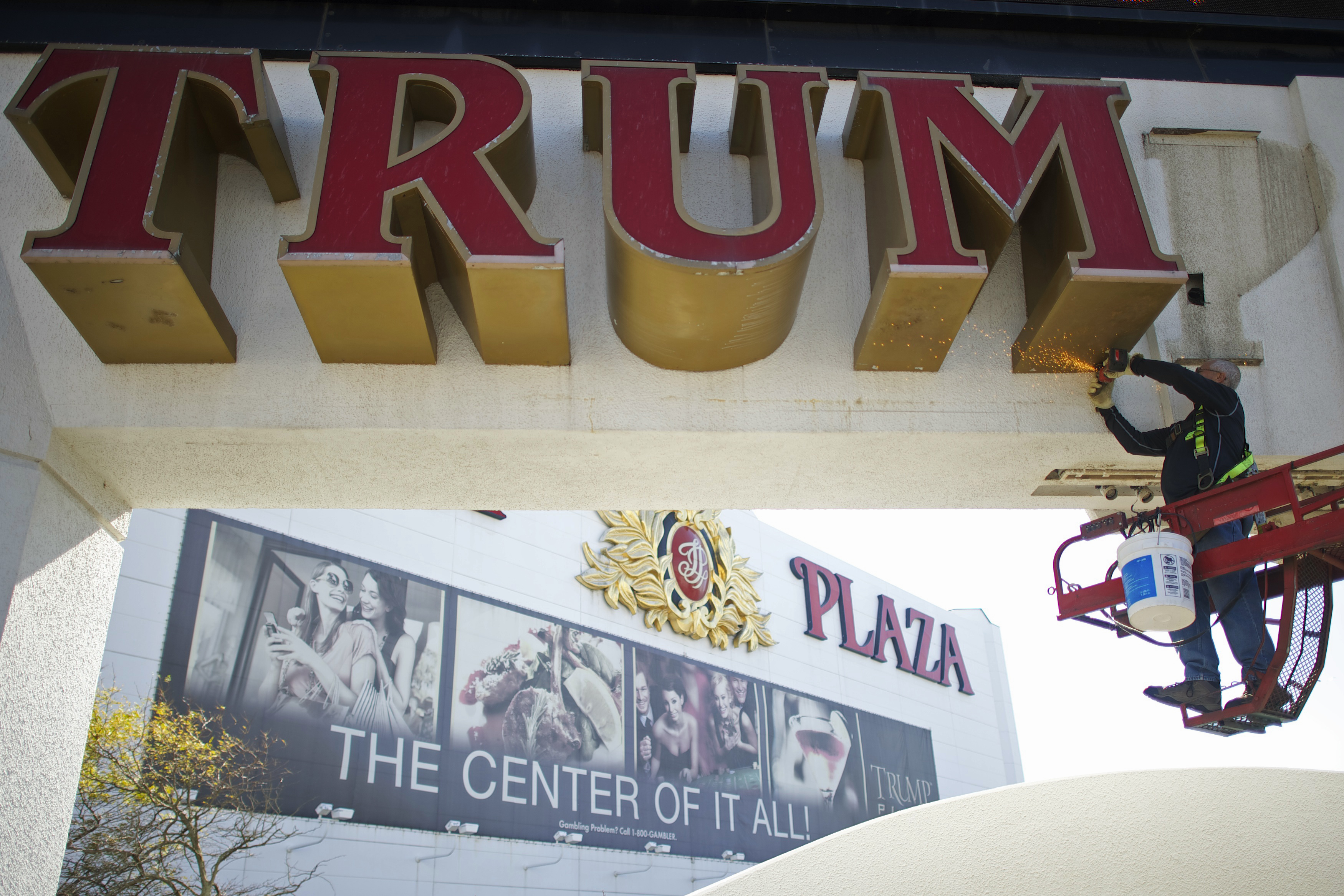 Williams, of Calvi Electric, saws mounts off the letter 'M' from the signage of Trump Plaza Casino in Atlantic City, New Jersey