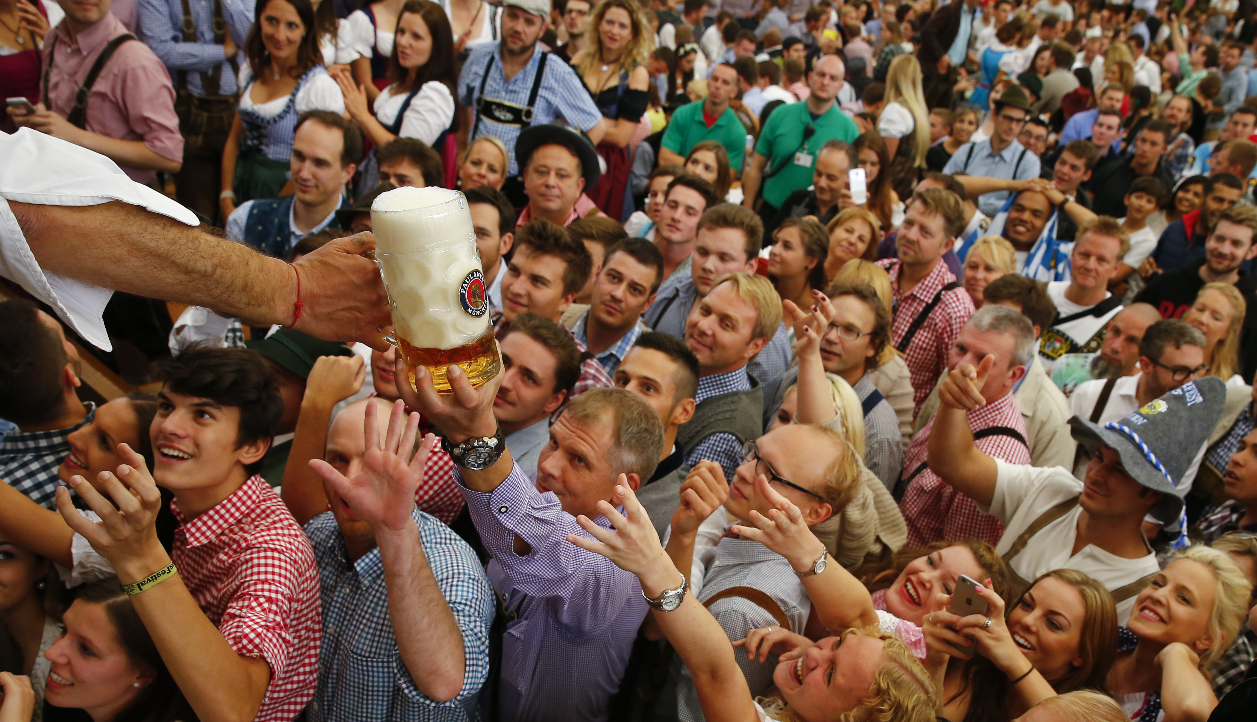 Visitors reach for one of the mugs of beer from the first barrel during the opening ceremony for the 182nd Oktoberfest in Munich