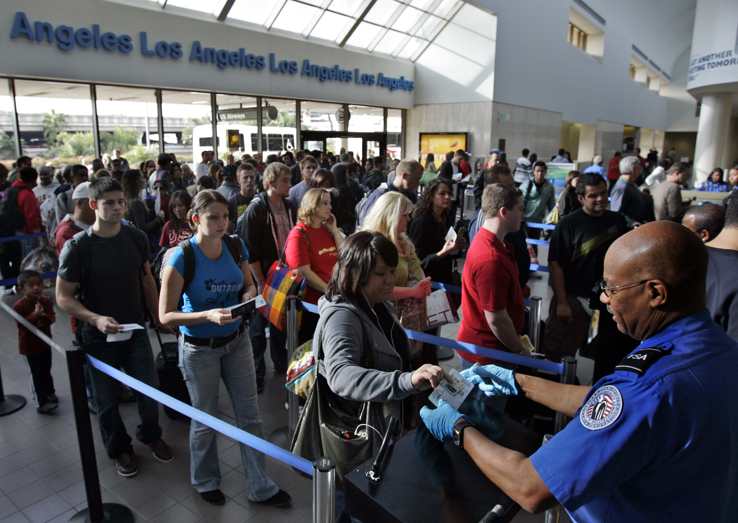 Travelers form a long security check line that is extended out of departure lounge at Los Angeles a
