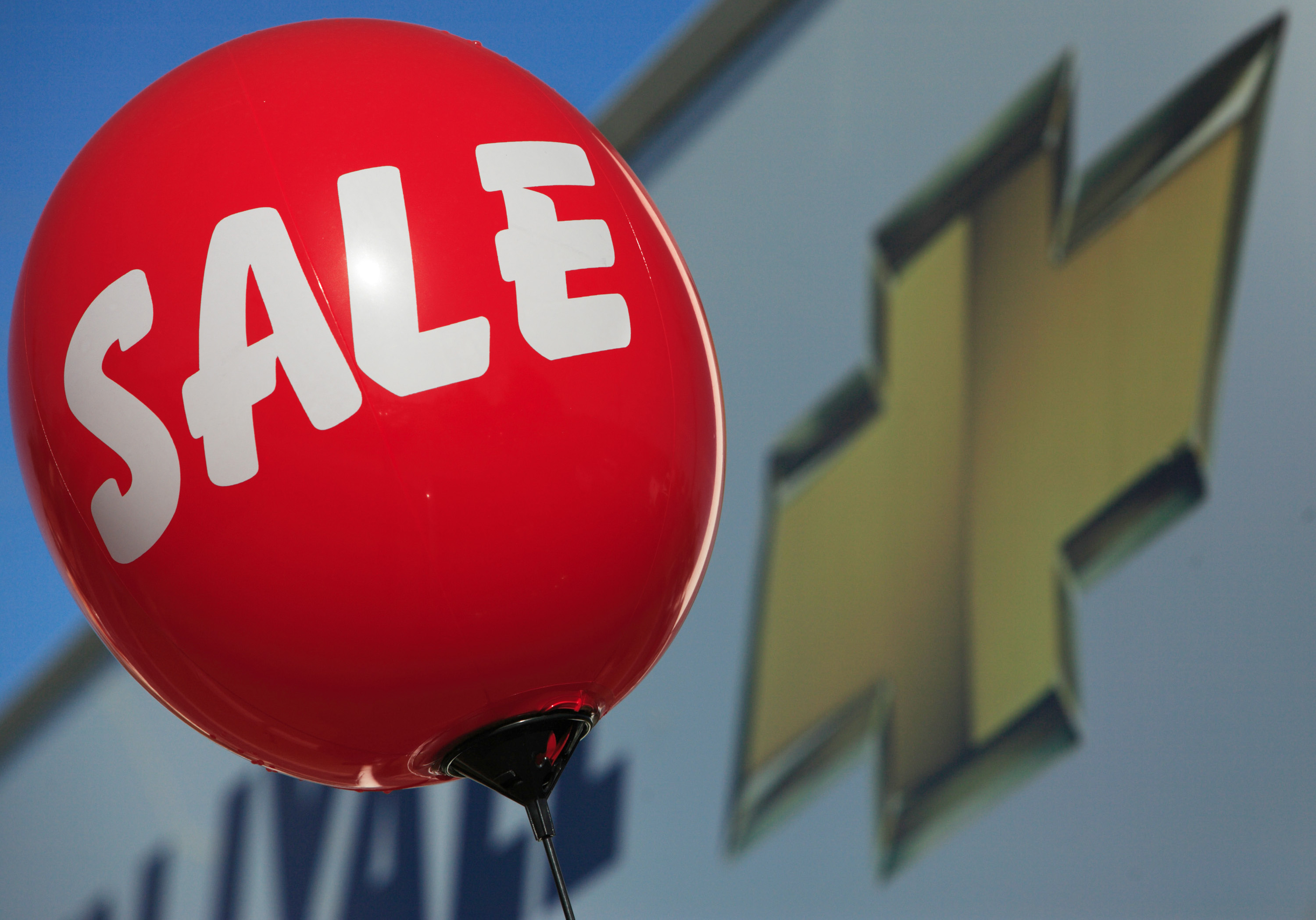 A balloon alerting consumers of a sale floats near a sign at