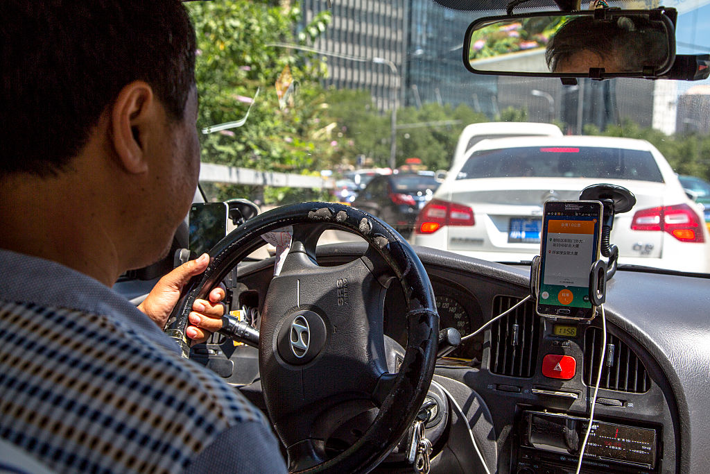 BEIJING, CHINA - 2015/08/04: A taxi driver is using Didi Dacha App while driving on the way. China Investment Corporation (CIC) has made an undisclosed investment in Chinese taxi-hailing app maker Didi Kuaidi. (Photo by Zhang Peng/LightRocket via Getty Images)