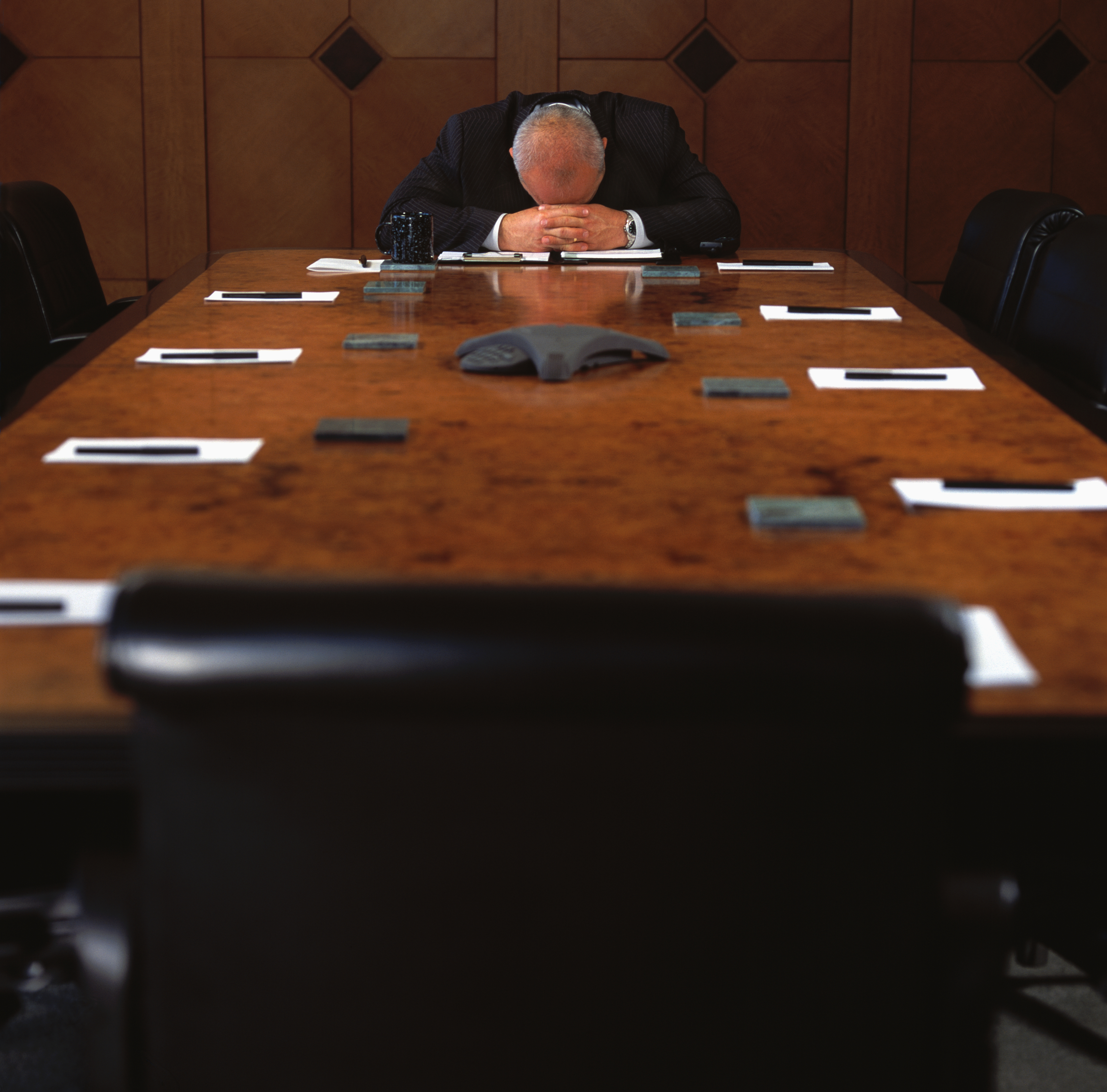 Man Sitting at Empty Conference Table with His Head Down