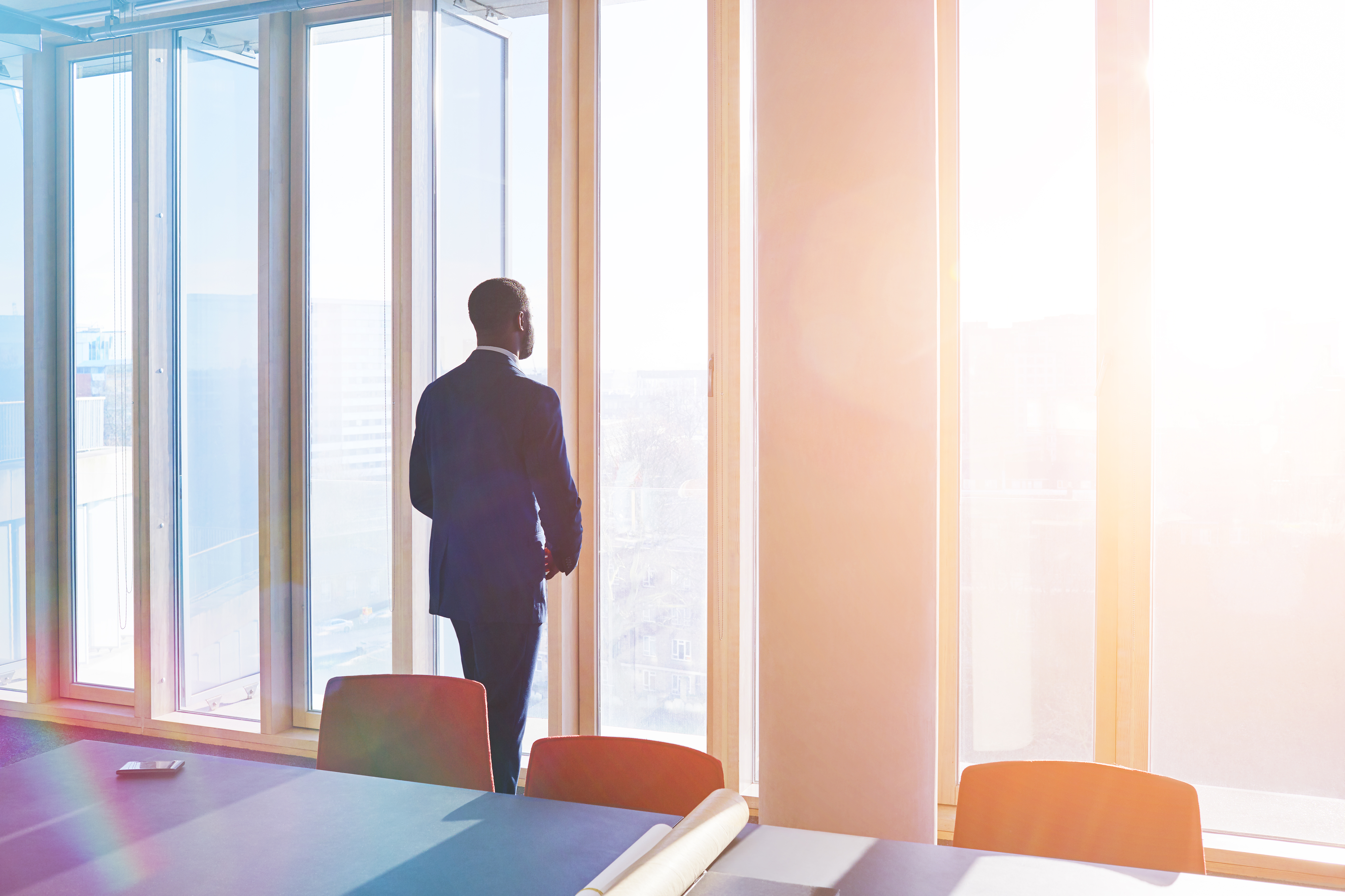Businessman looks out of office window over city