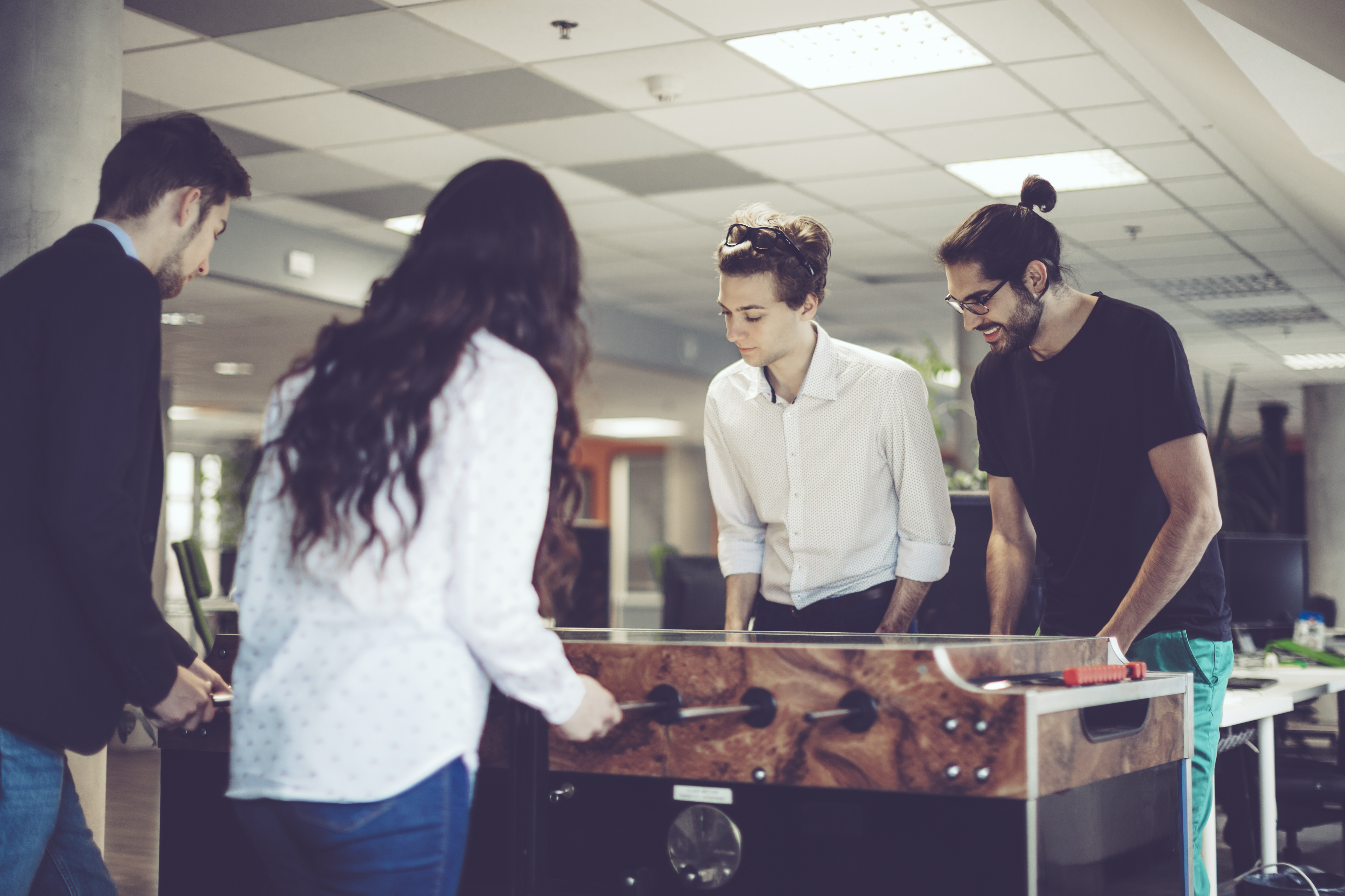 Young adults are playing foosball at work
