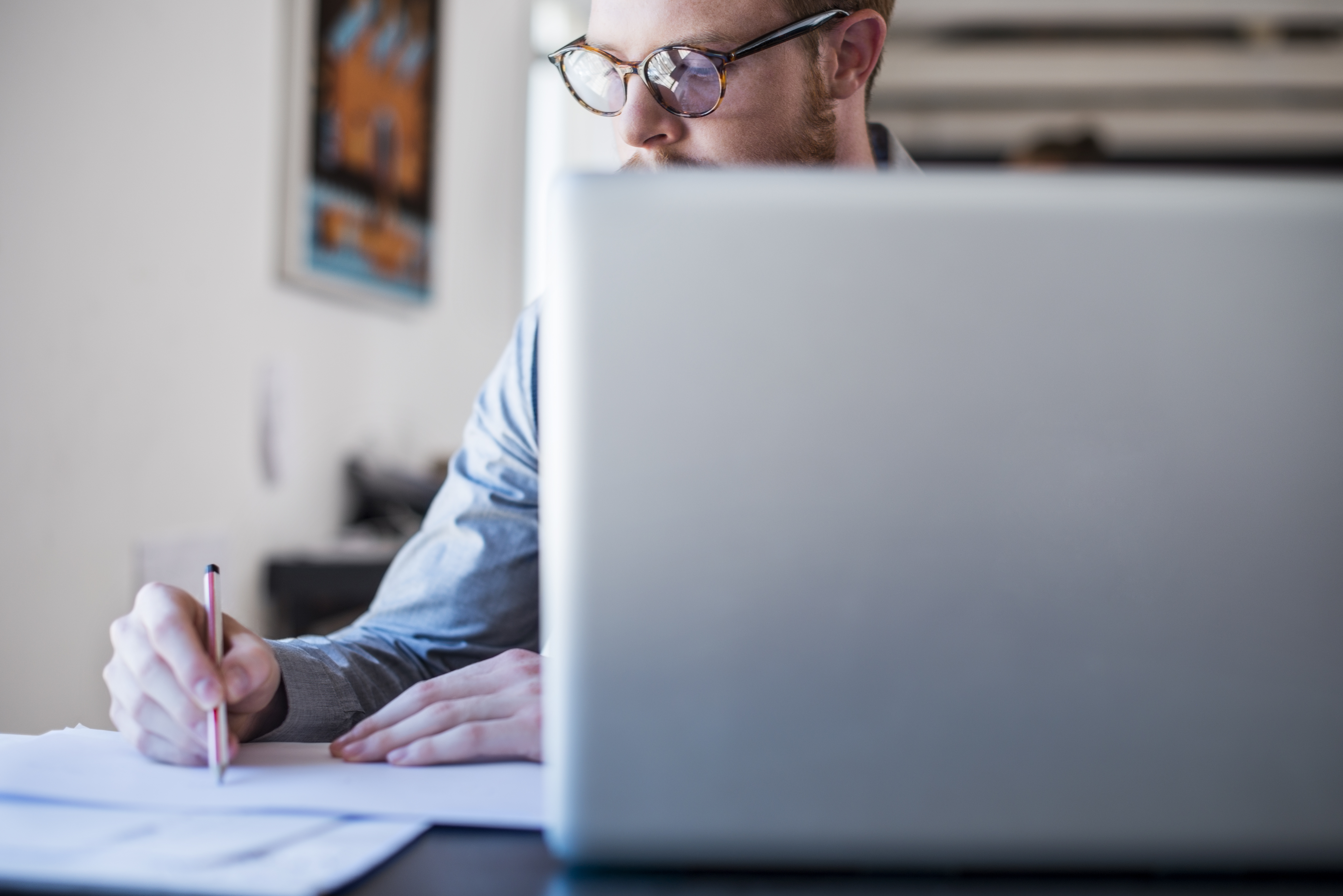 Businessman writing notes at laptop desk