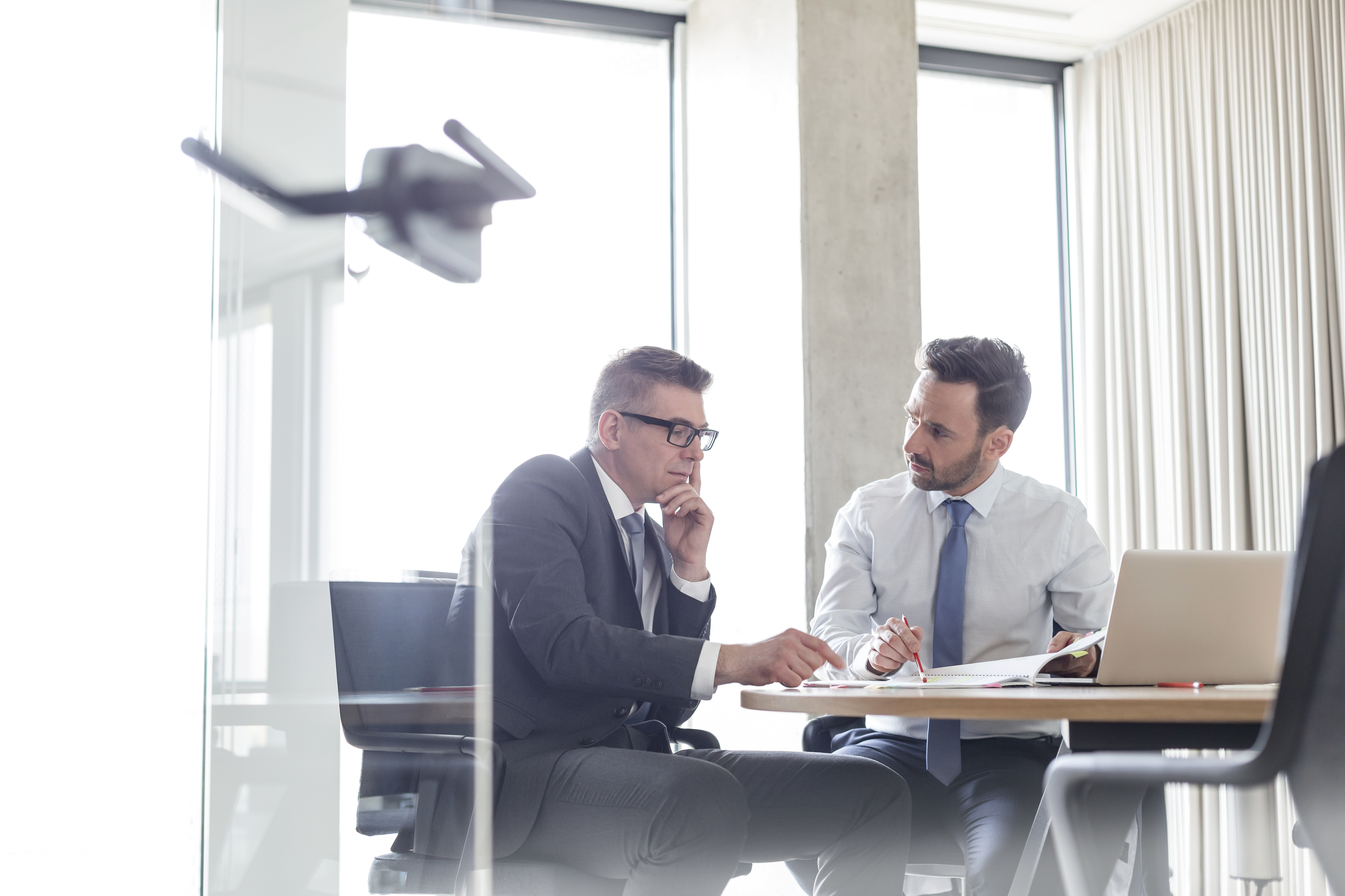 Businessmen reviewing and discussing report in conference room