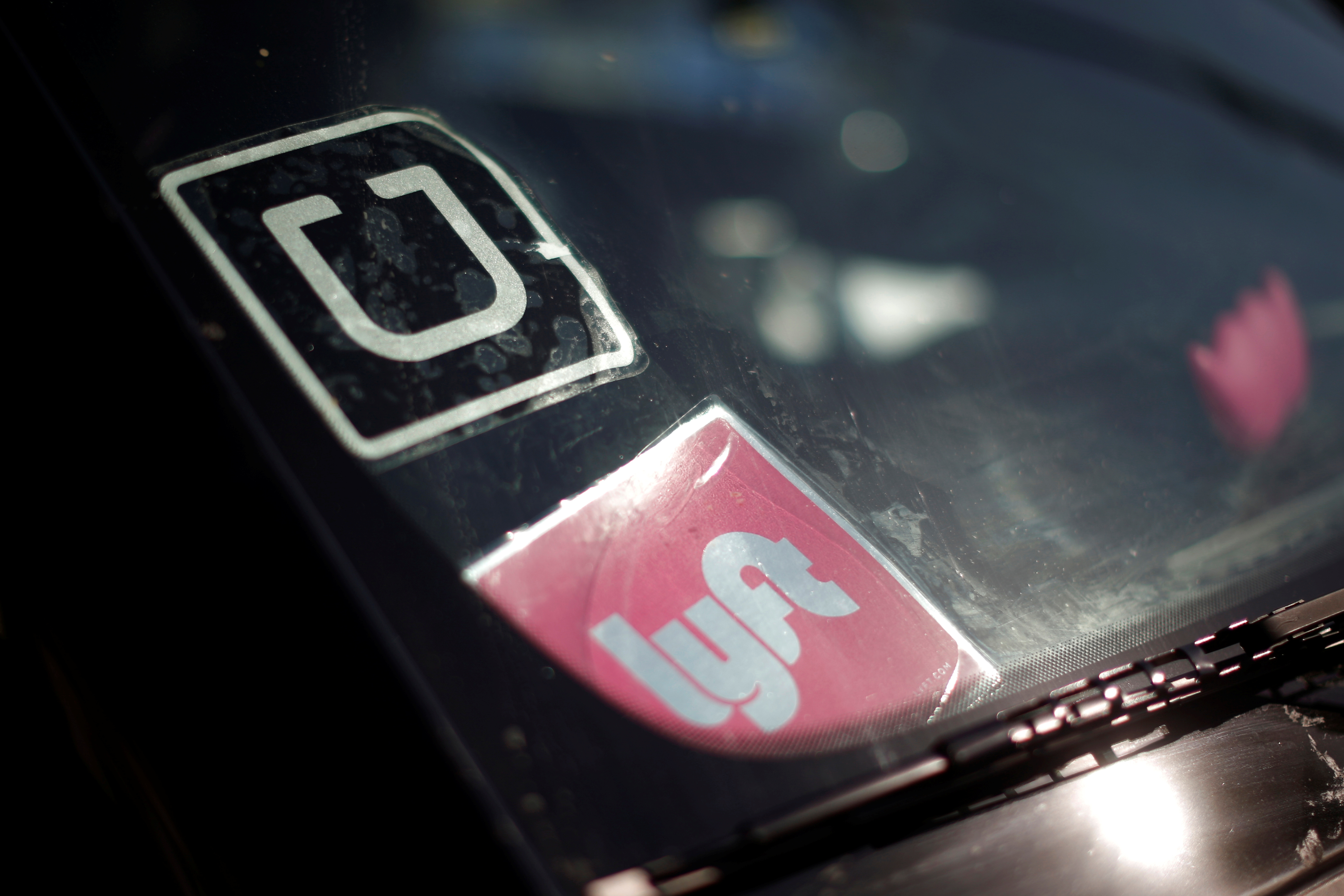 A driver displays Uber and Lyft ride sharing signs on his car windscreen in Santa Monica