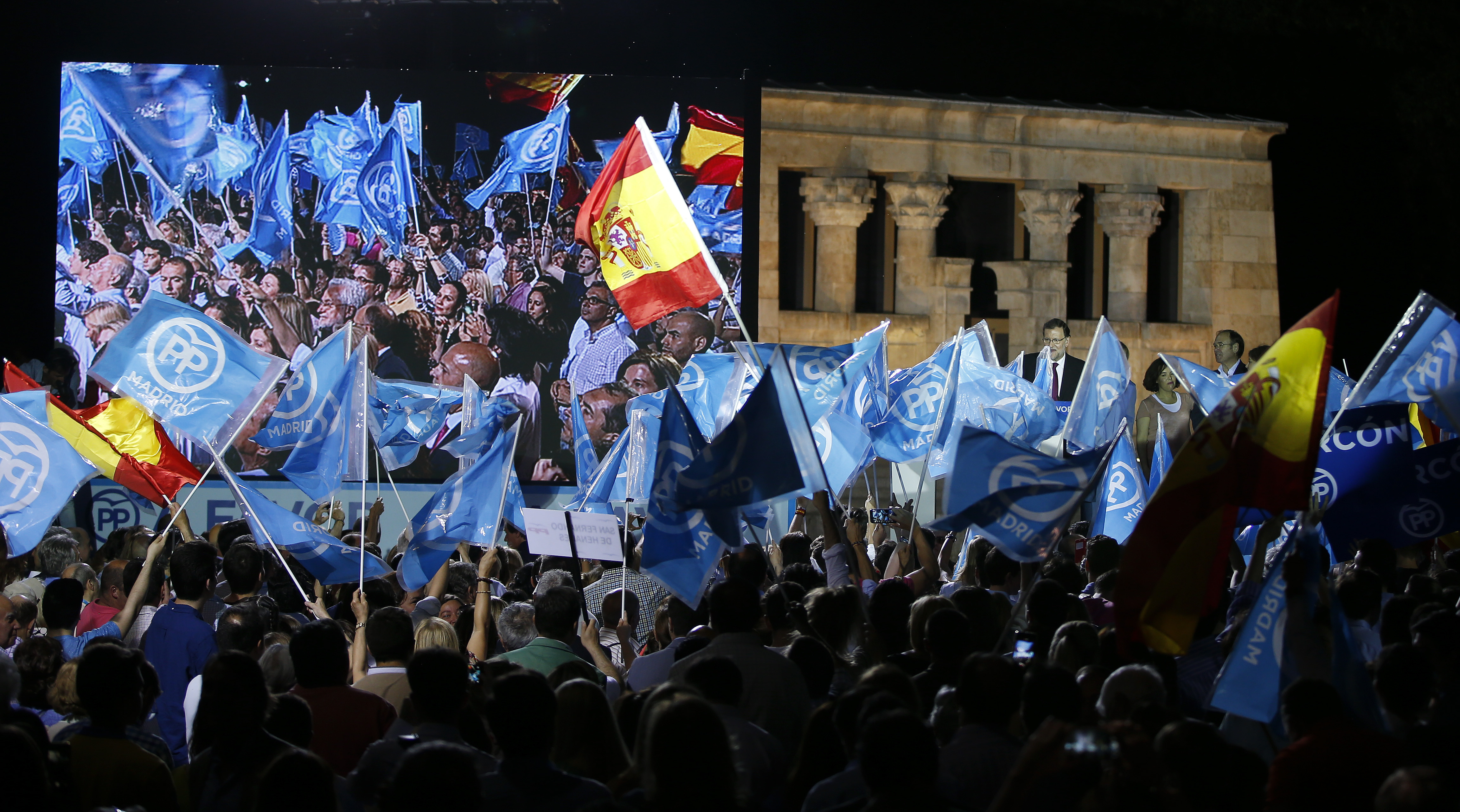 Supporters wave flags as People's Party (PP) leader Mariano Rajoy delivers a speech during a rally at the start of the official campaign period for Spain's general election in Madrid