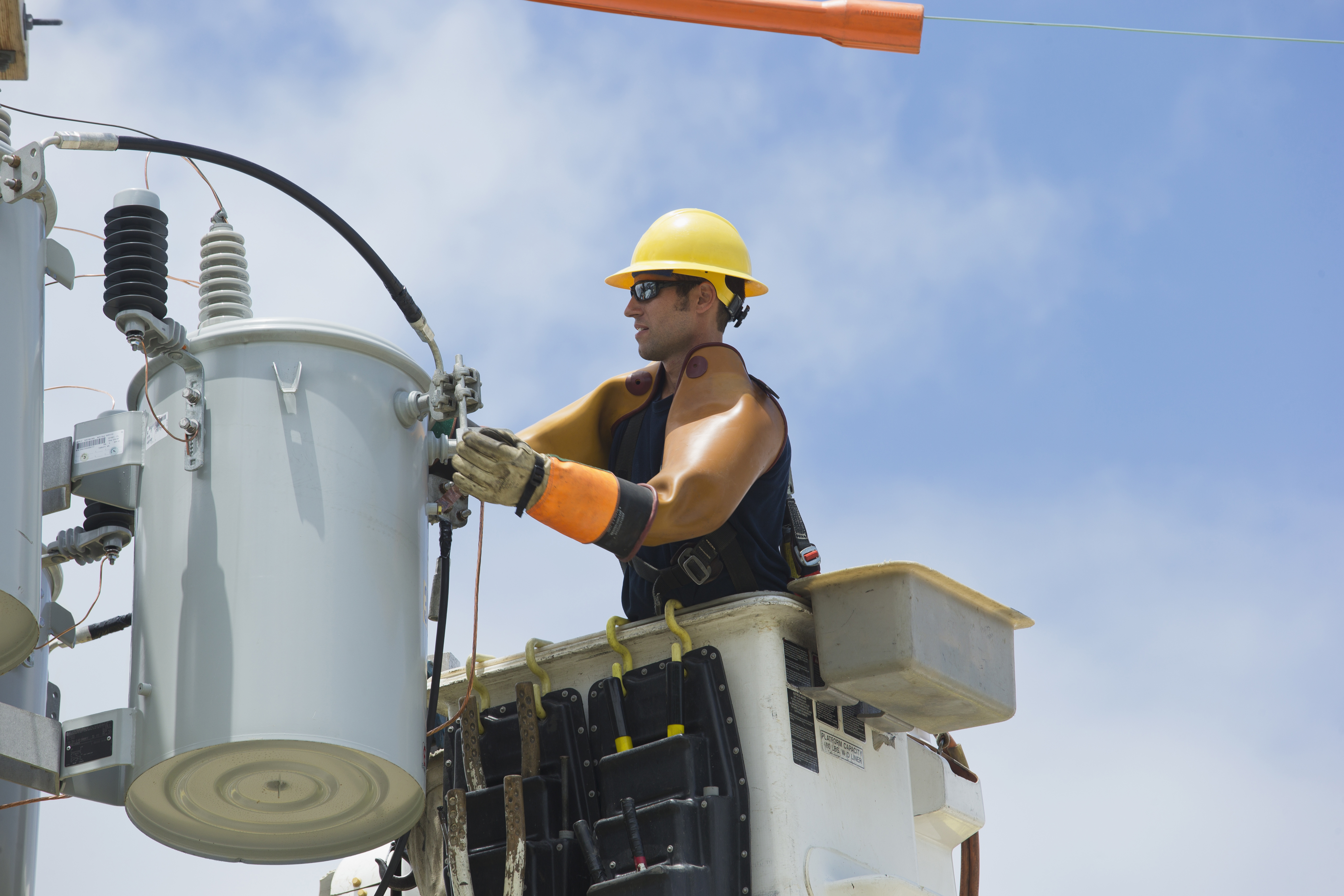 Caucasian worker in cherry picker repairing power line
