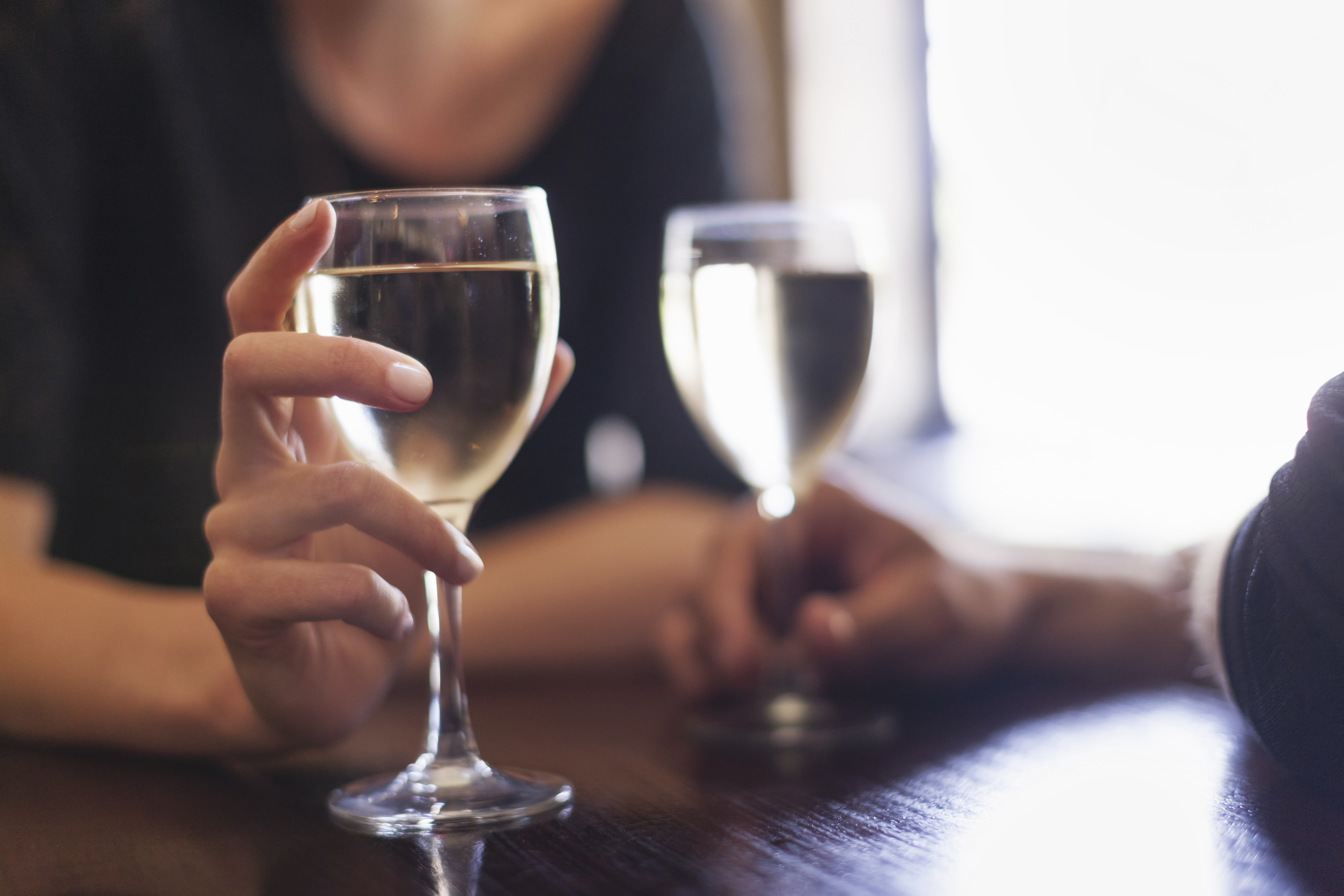 Two people, a couple sitting in a bar having a glass of chilled white wine.