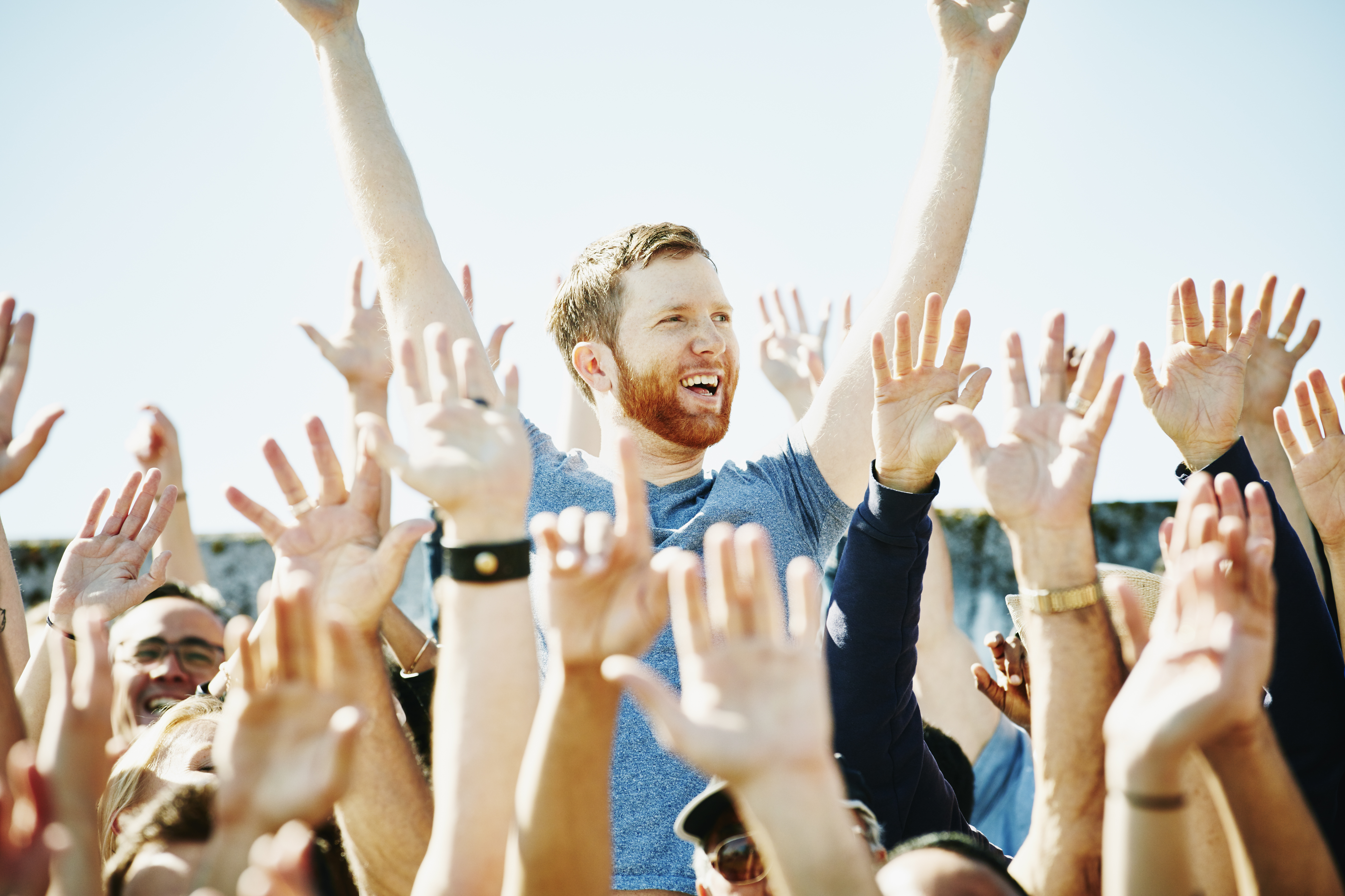 Man cheering in crowd with arms raised