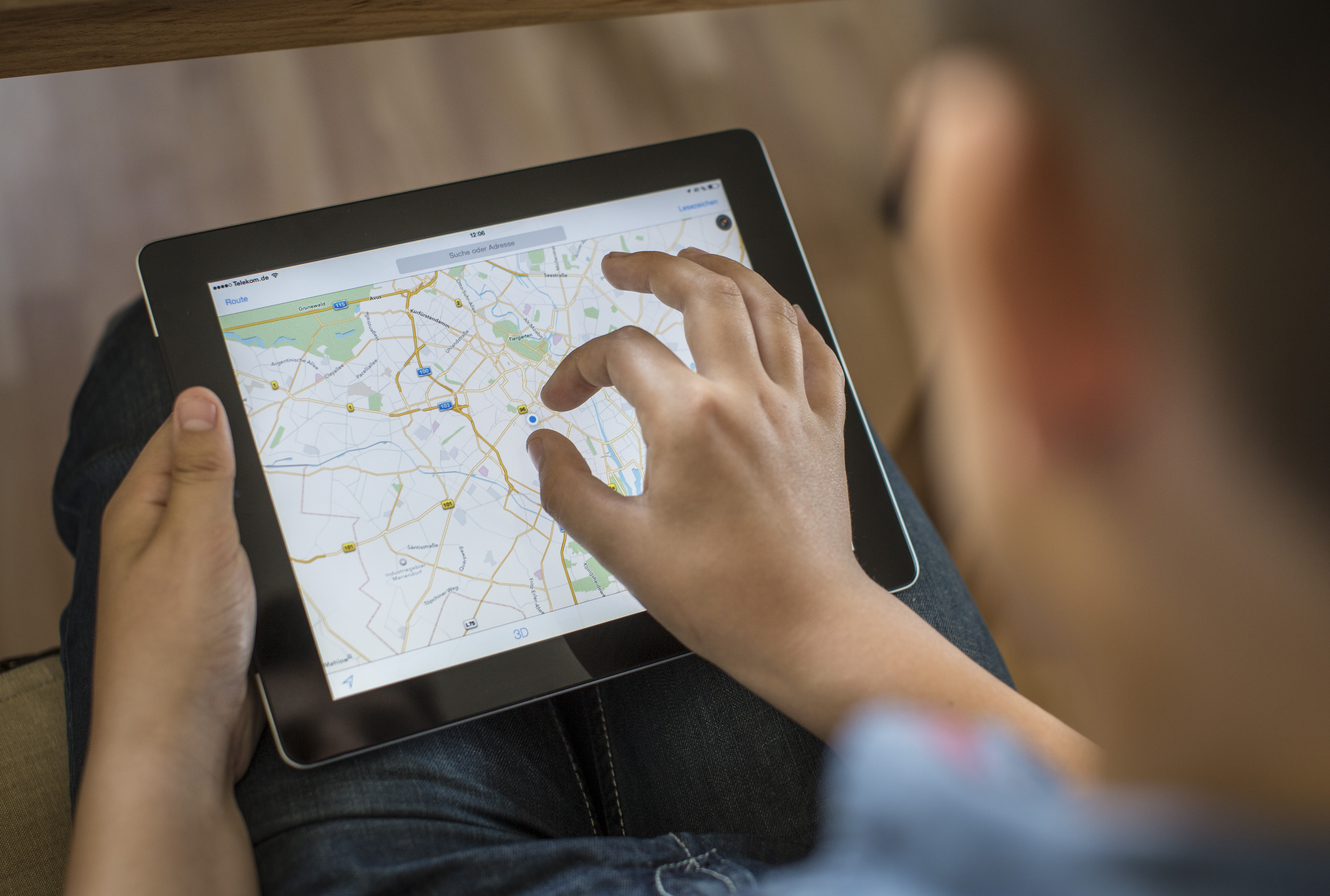 Boy holding an iPad on which Google Maps is opened.