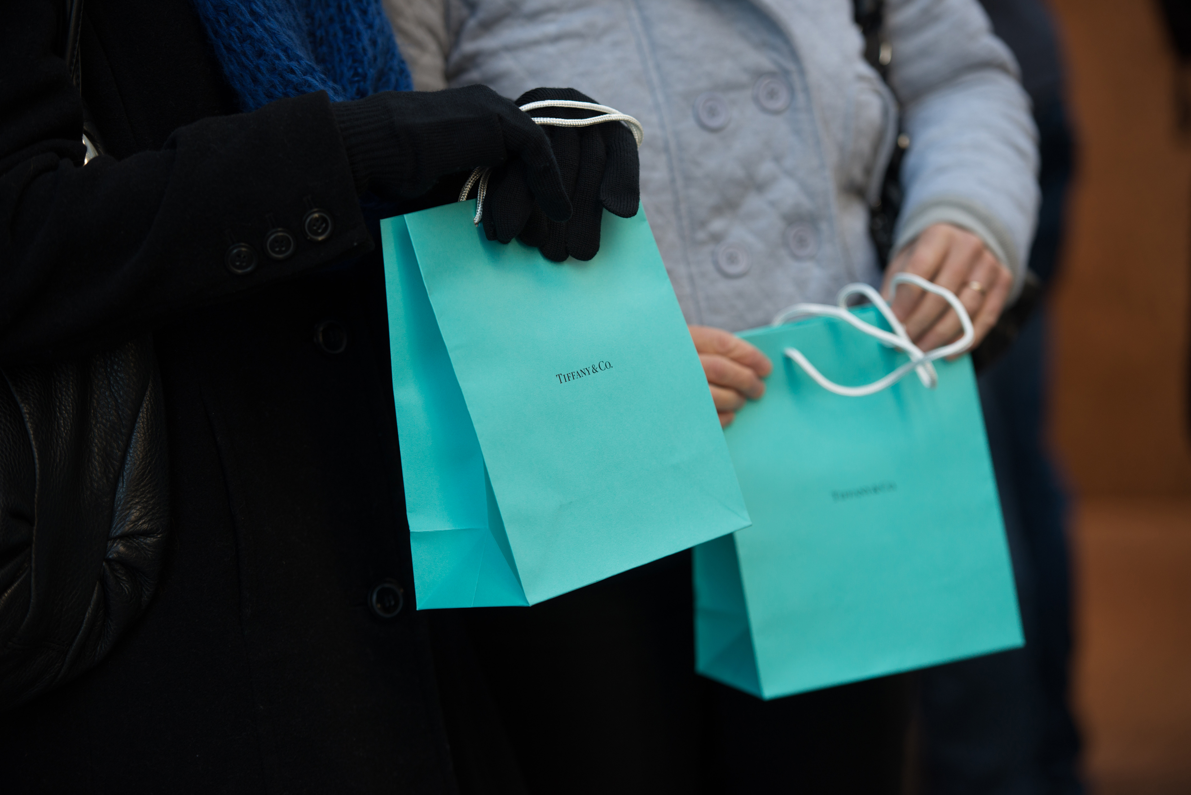 Customers carry Tiffany & Co. shopping bags outside the company's flagship store in New York.