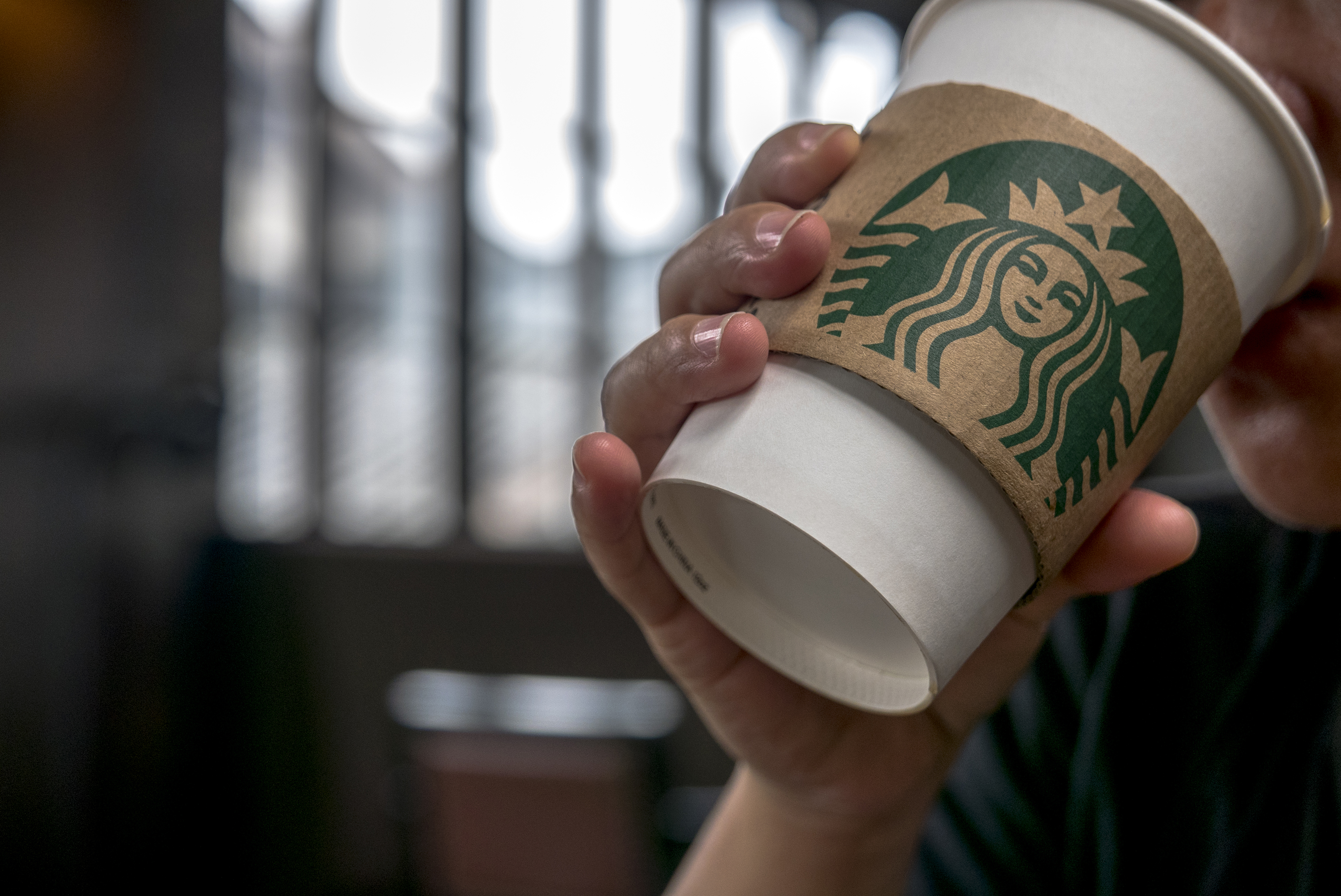 Customer drinks coffee in a Starbucks cafe.  Starbucks is
