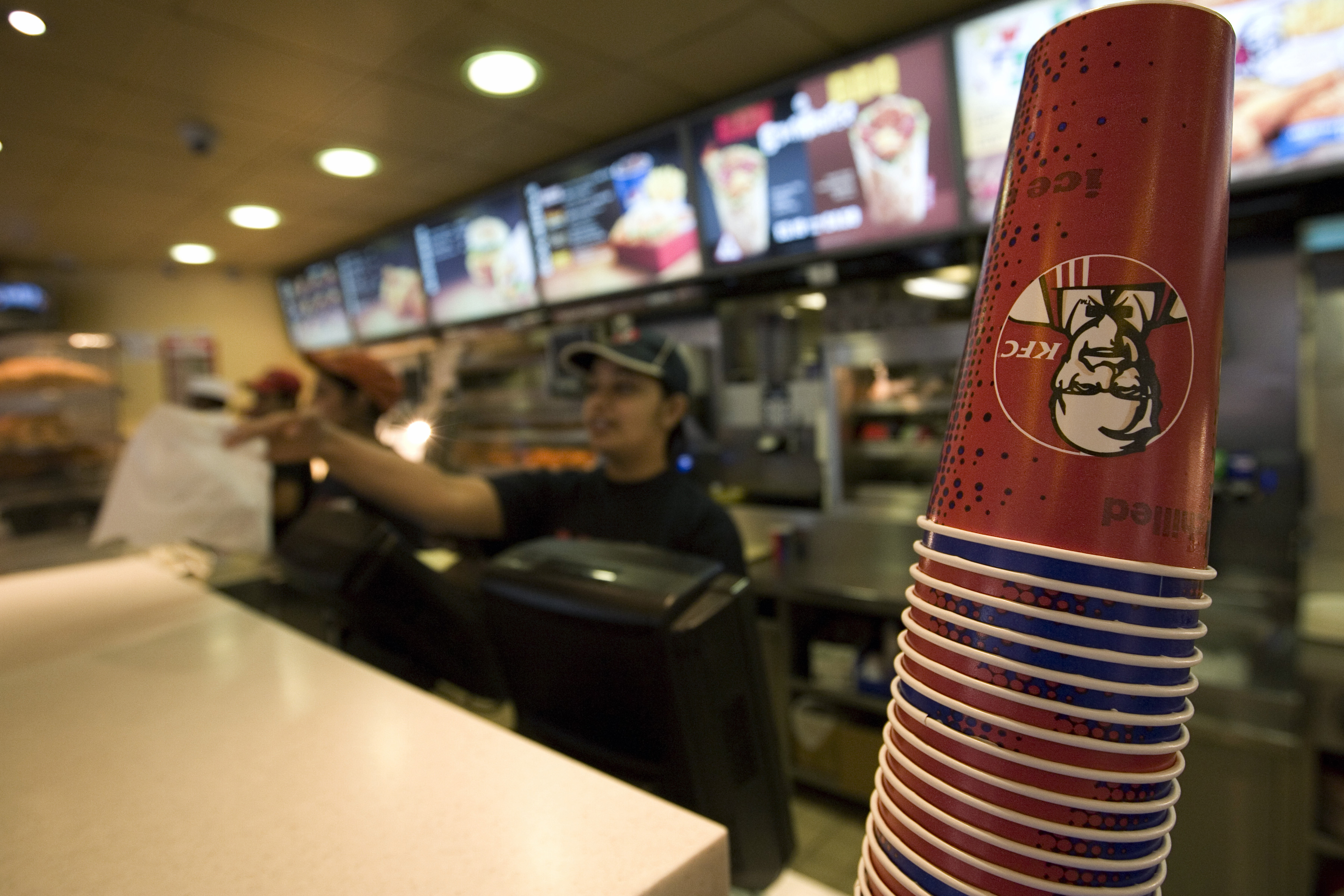 A KFC employee serving a hungry customer in the restaurant on Oxford Street, Central London