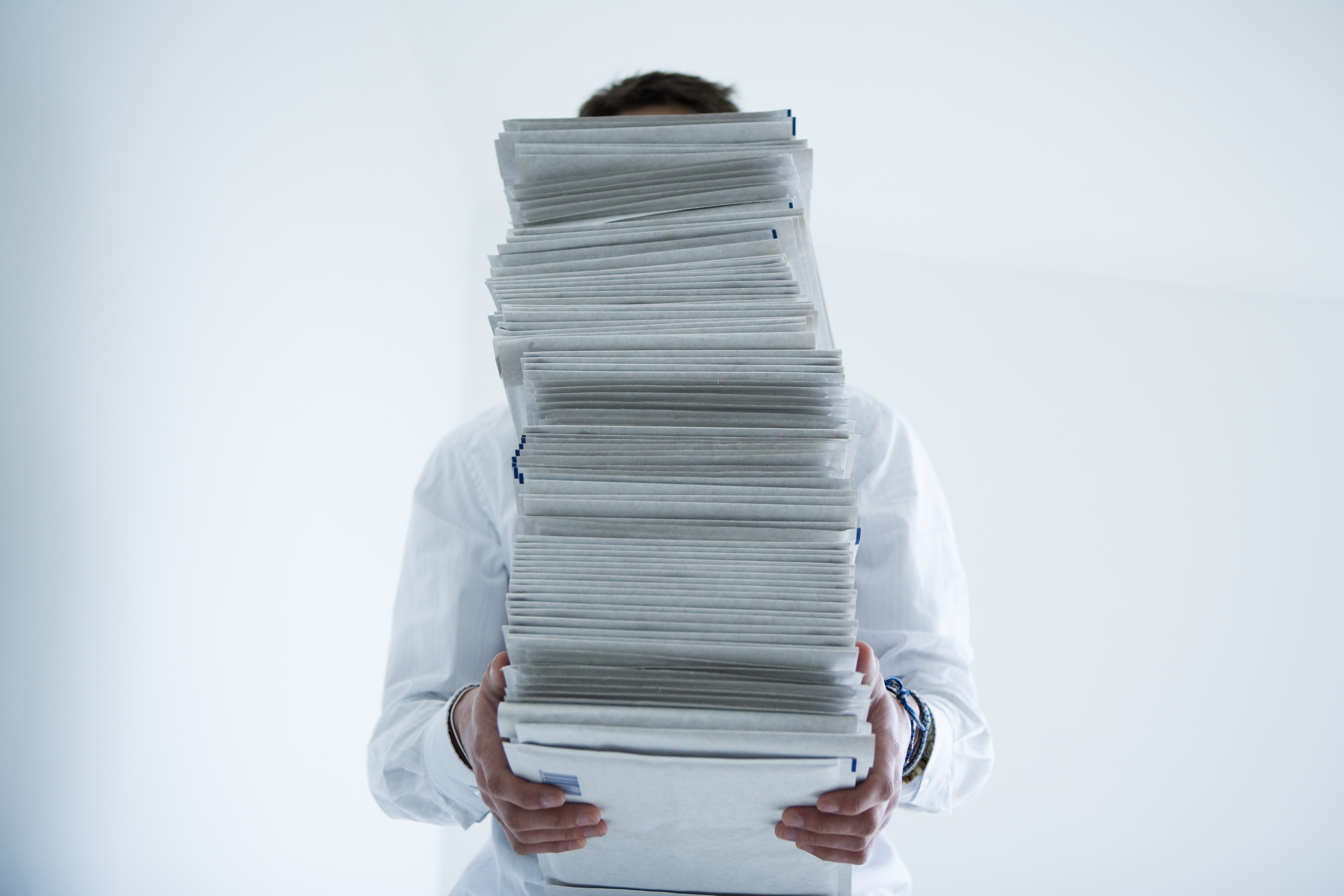 Man holding stack of paper in front of face
