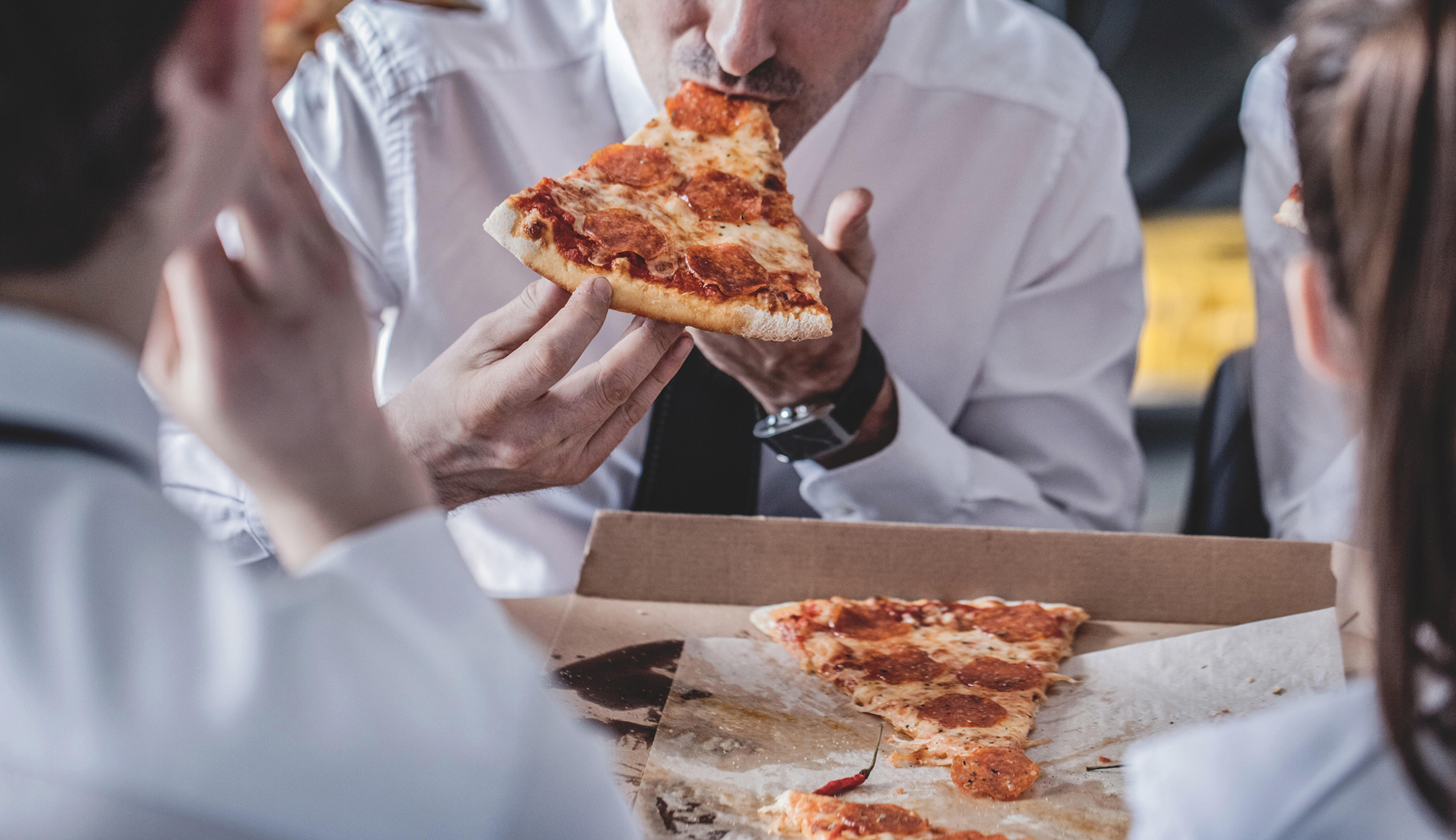 Business team eating pizza in office sitting around the table