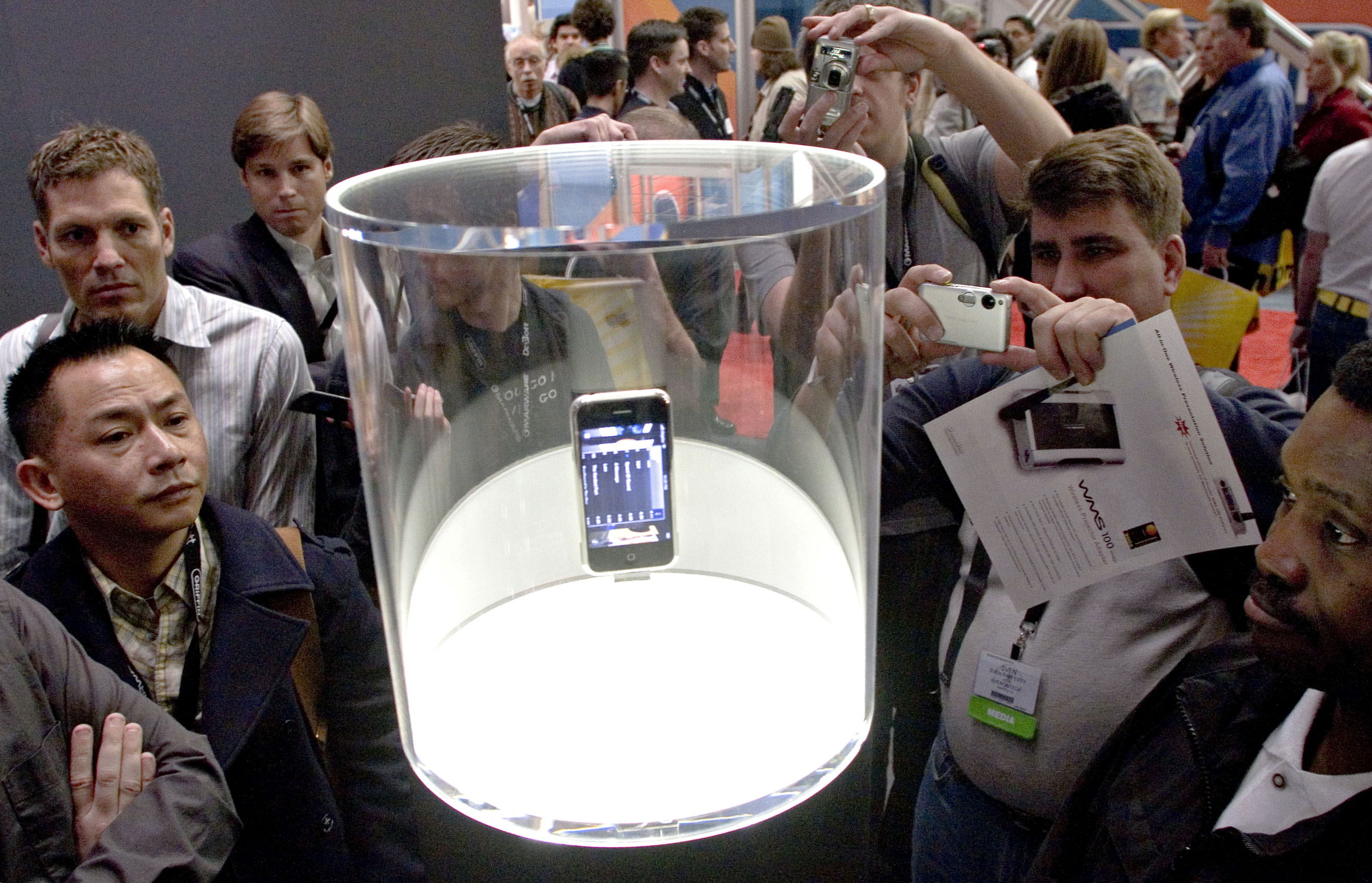 MacWorld attendees look over an iPhone on display during Mac