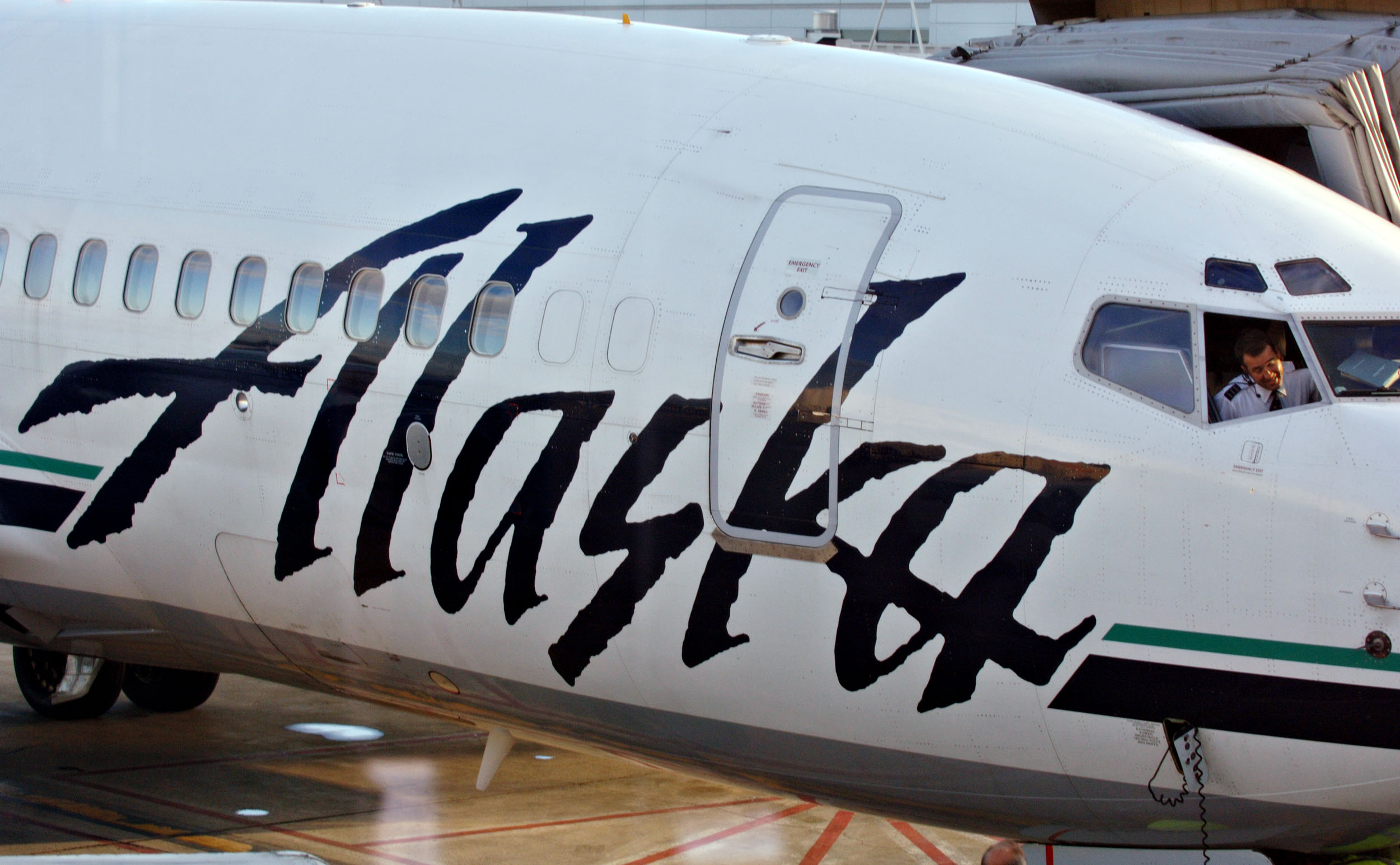 An Alaska Airlines pilot talks to ground crew from the cockpit of a jet sitting at a gate at Ted Stevens International Airport in Anchorage.
