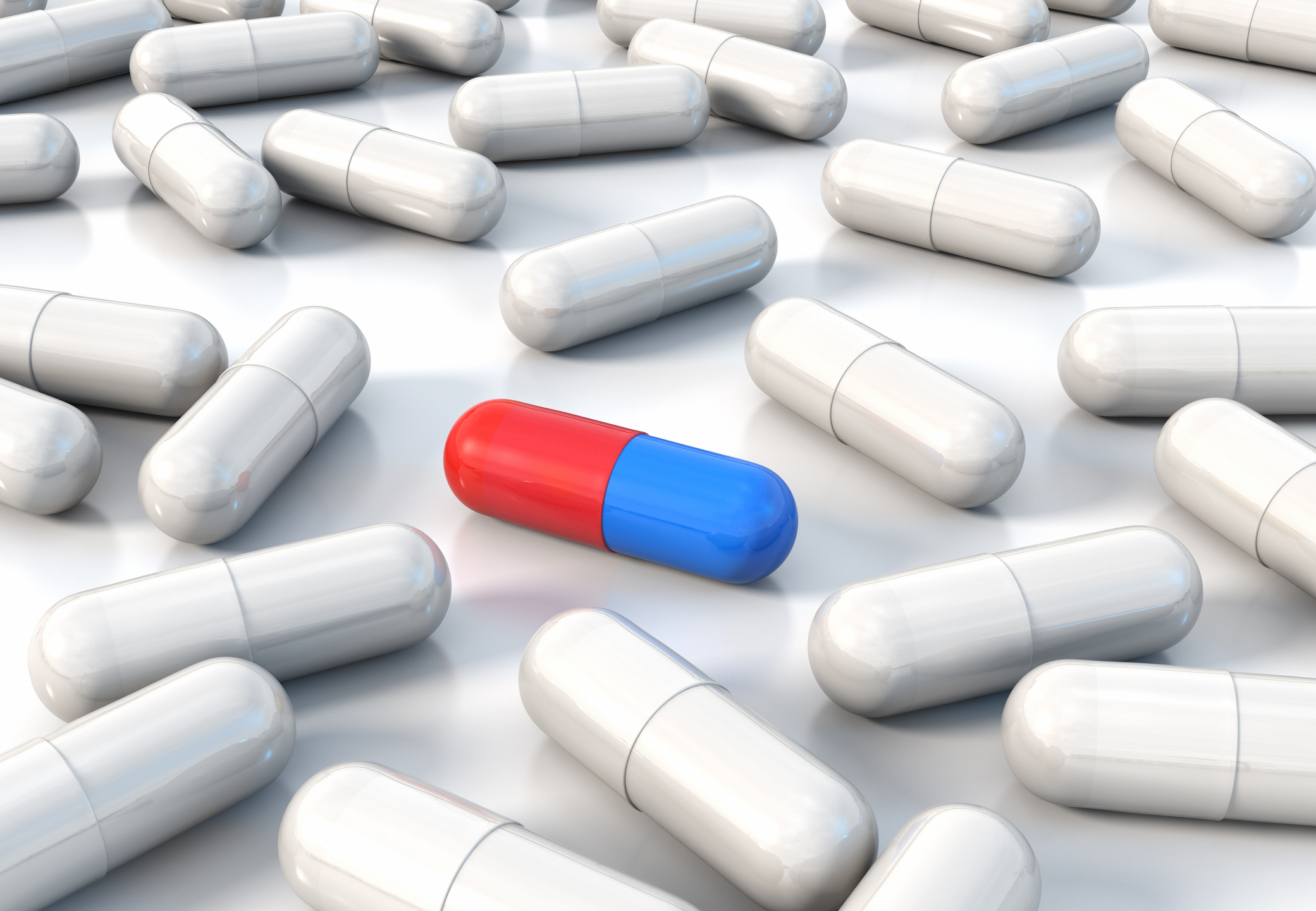Blue and red capsule amongst plain white ones