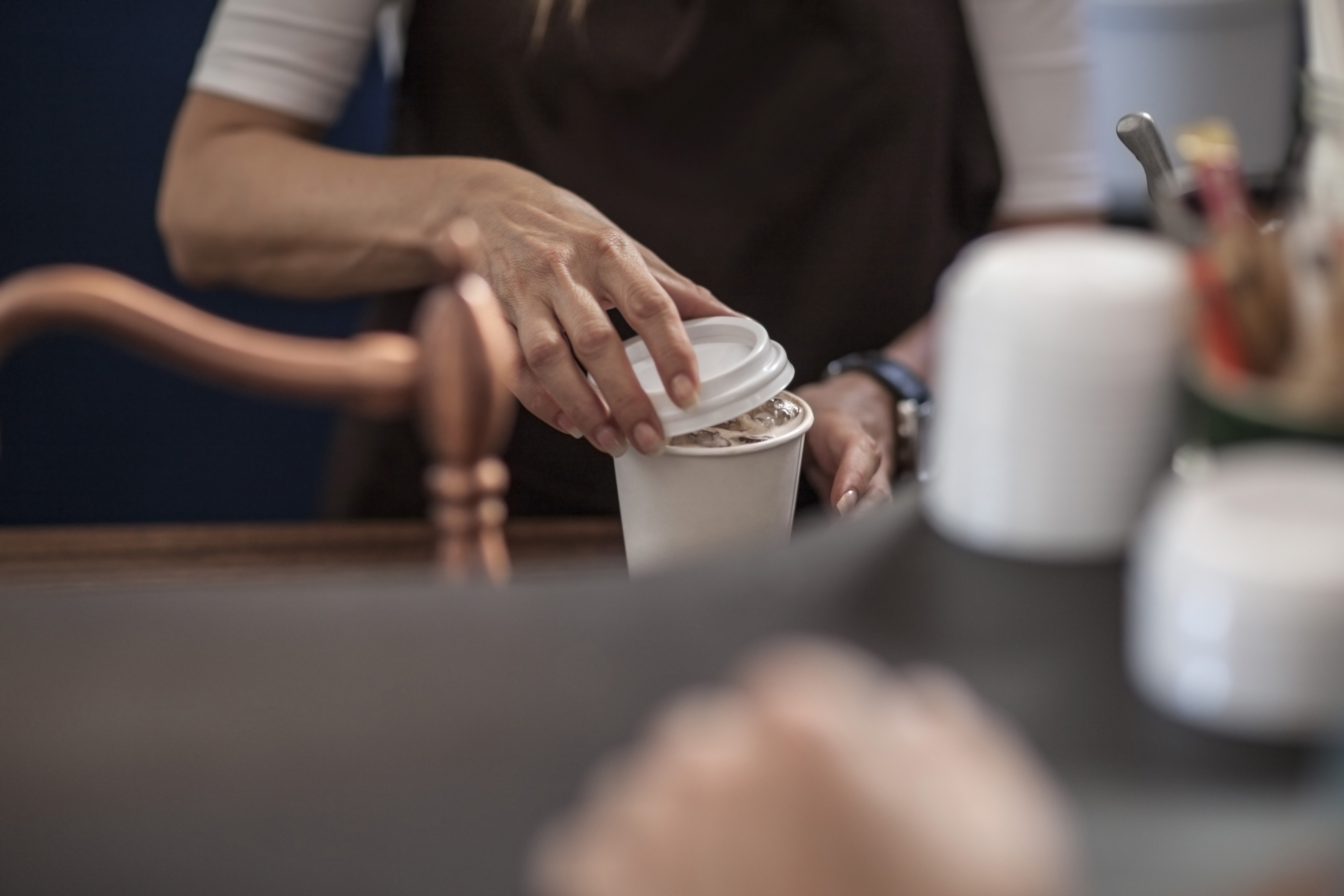 Barista closing lid of disposable coffee cup