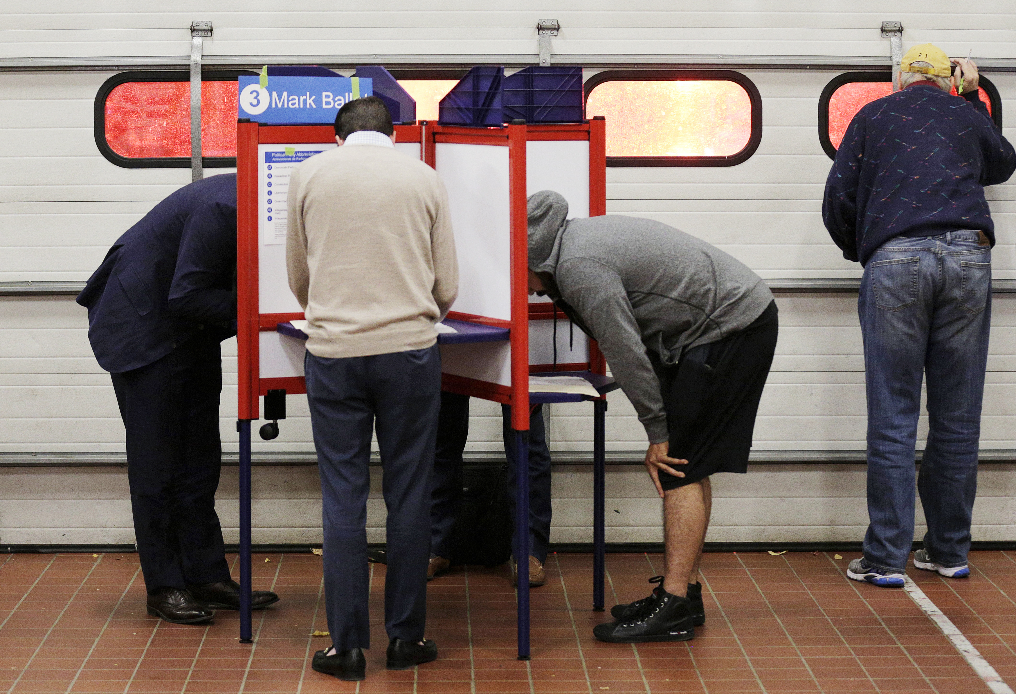Voters look over their ballots at a fire station while a crew leaves on an emergency call during the U.S. presidential election in Arlington